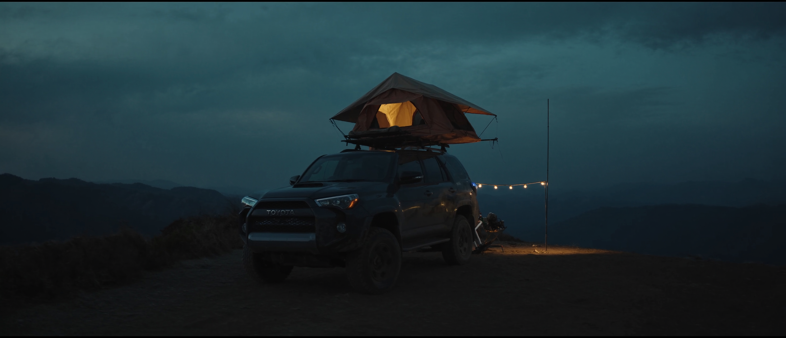 Overlanding Toyota 4Runner with rooftop tent on a mountain ridge at dusk