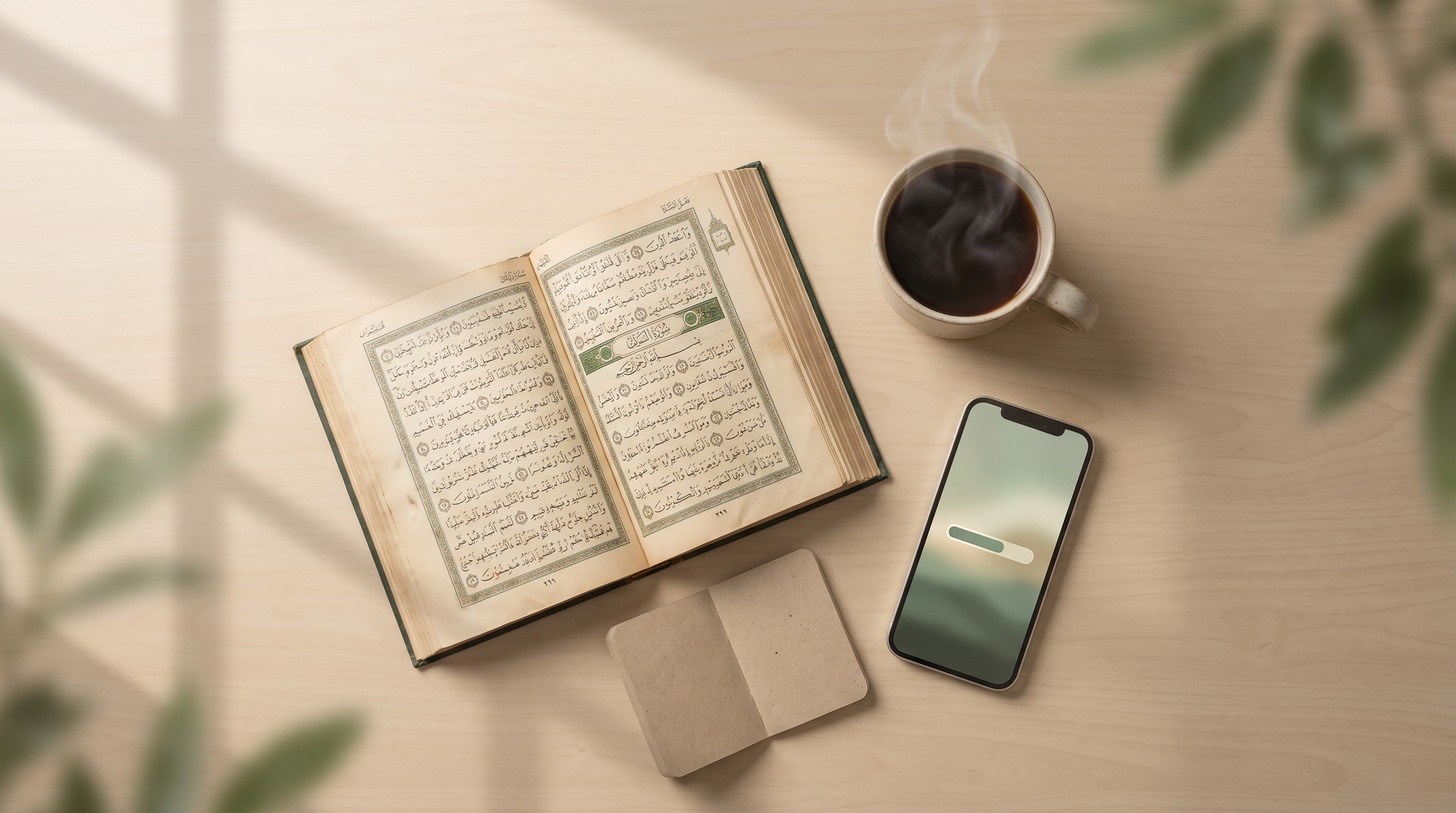 Overhead view of an open Qur'an, coffee, and a notebook on a wooden desk in soft morning light.