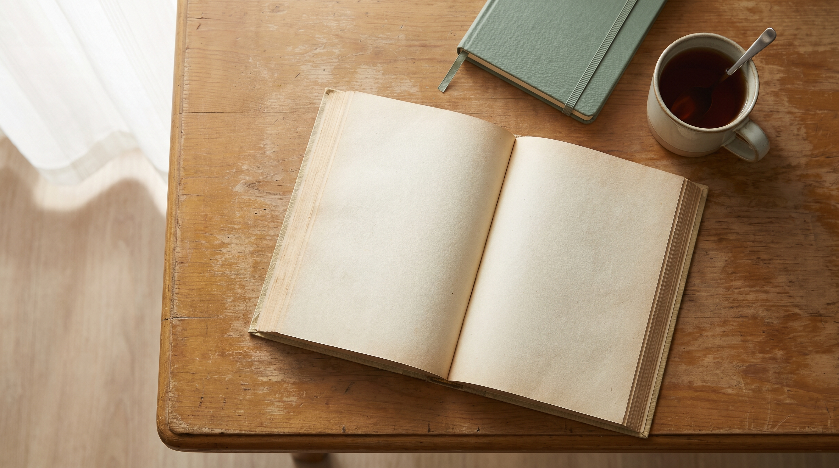 Overhead view of an open Mushaf on a wooden desk beside a notebook and a cup of tea in warm morning light.