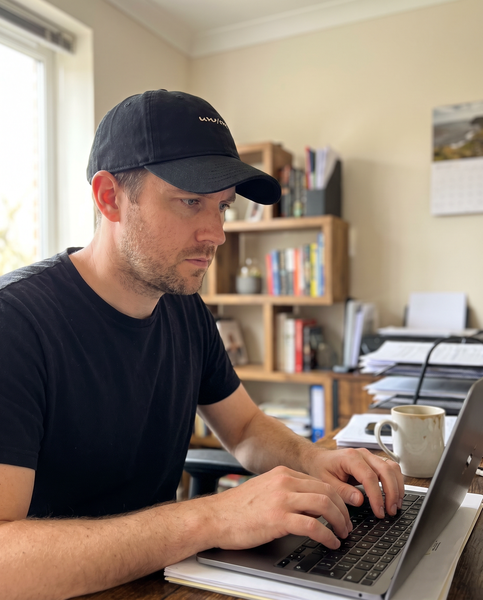 Person working calmly and focused at a desk, cap on