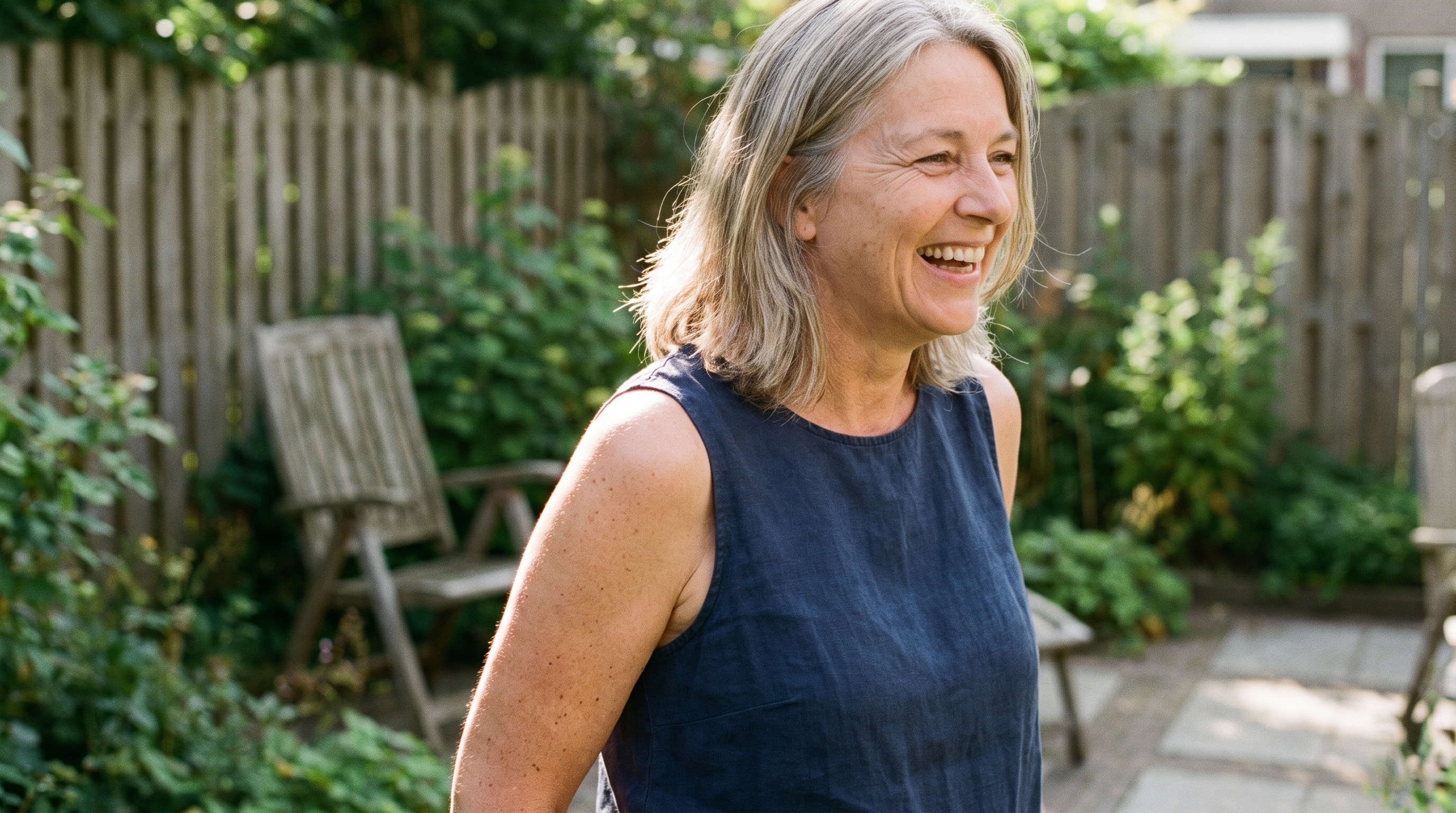Vrouw van rond de vijftig met blote armen in haar tuin