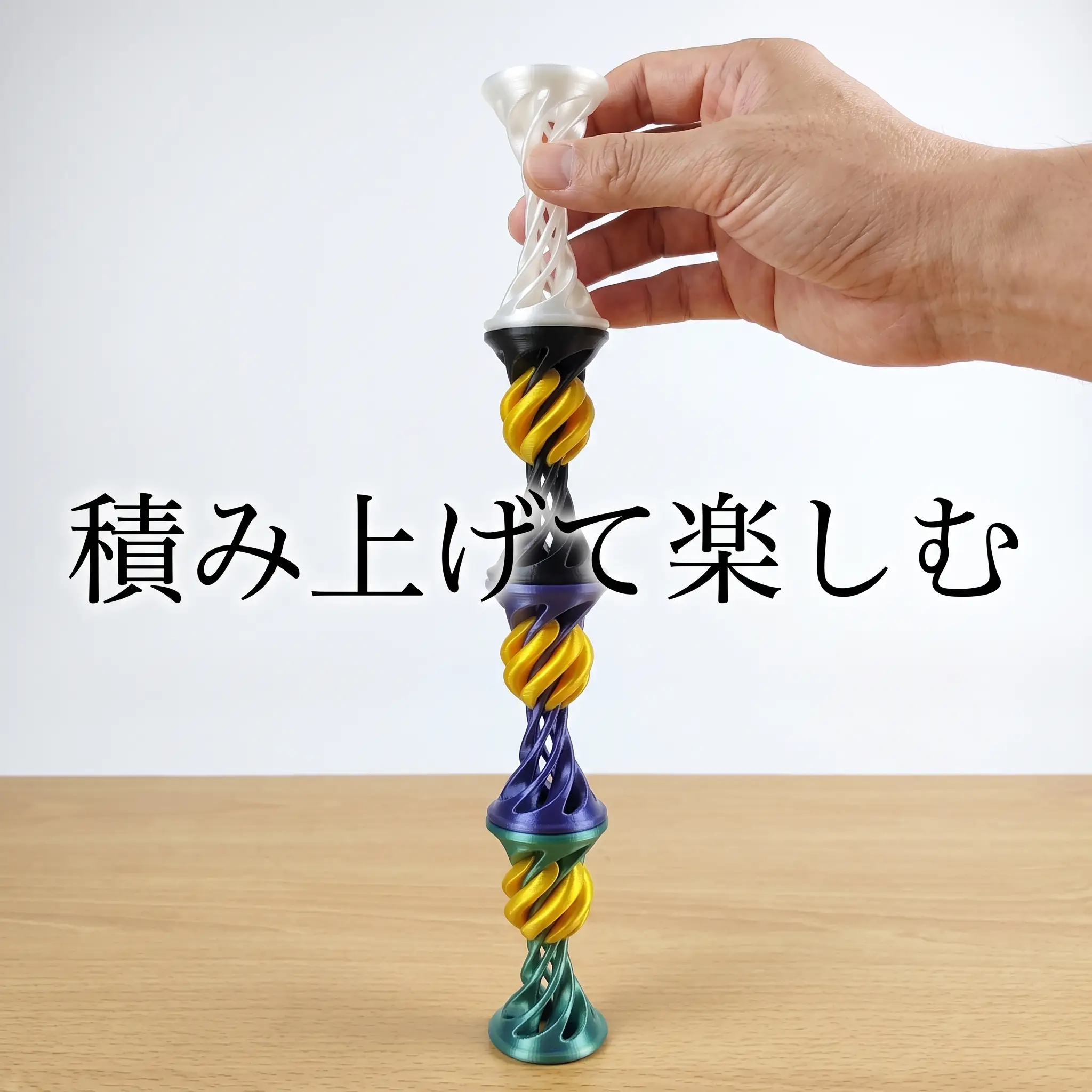 色違いを縦に継ぎ足した虹色のタワーを指先でバランスさせる様子