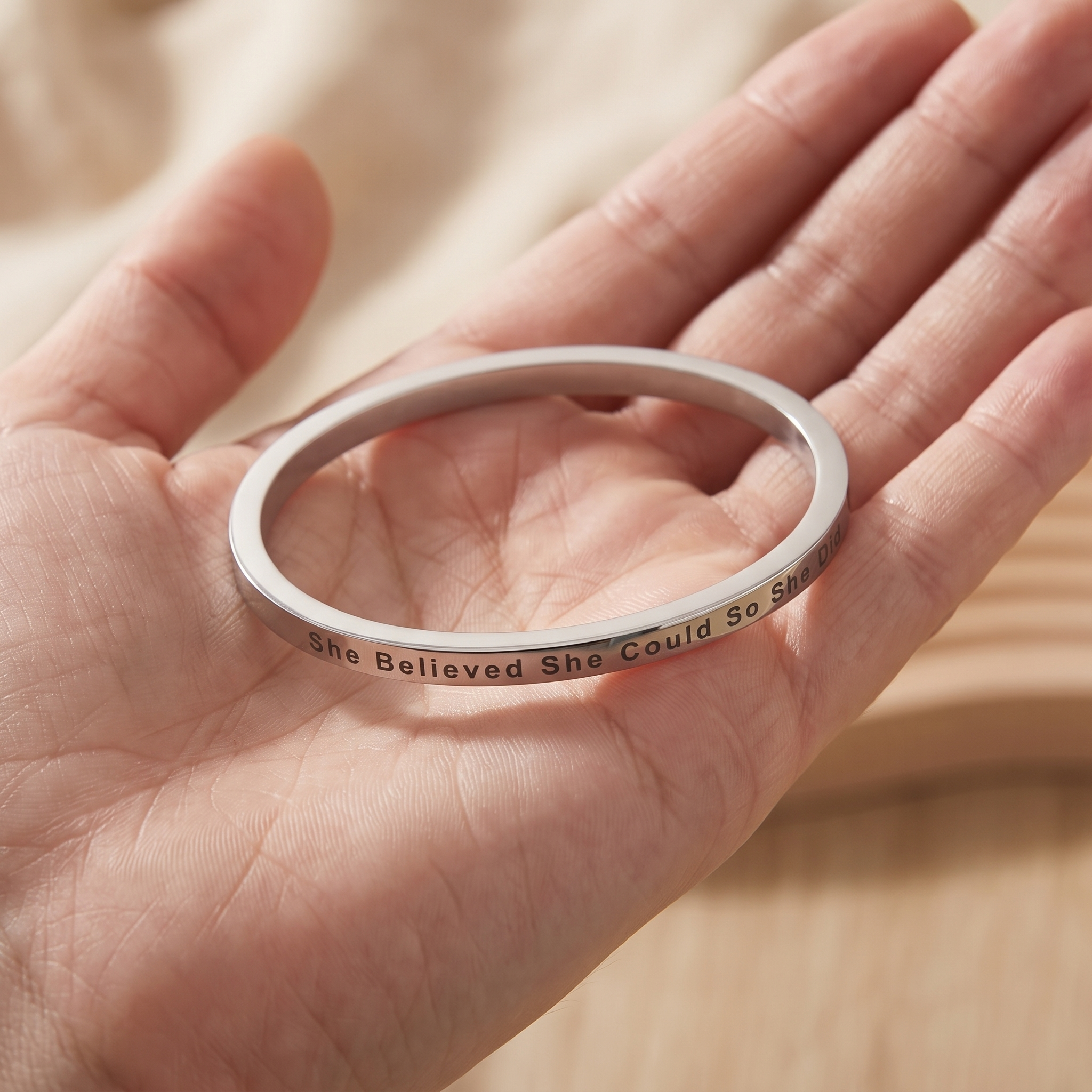 Hands holding an old birthday card beside a pendant engraved with a single first name