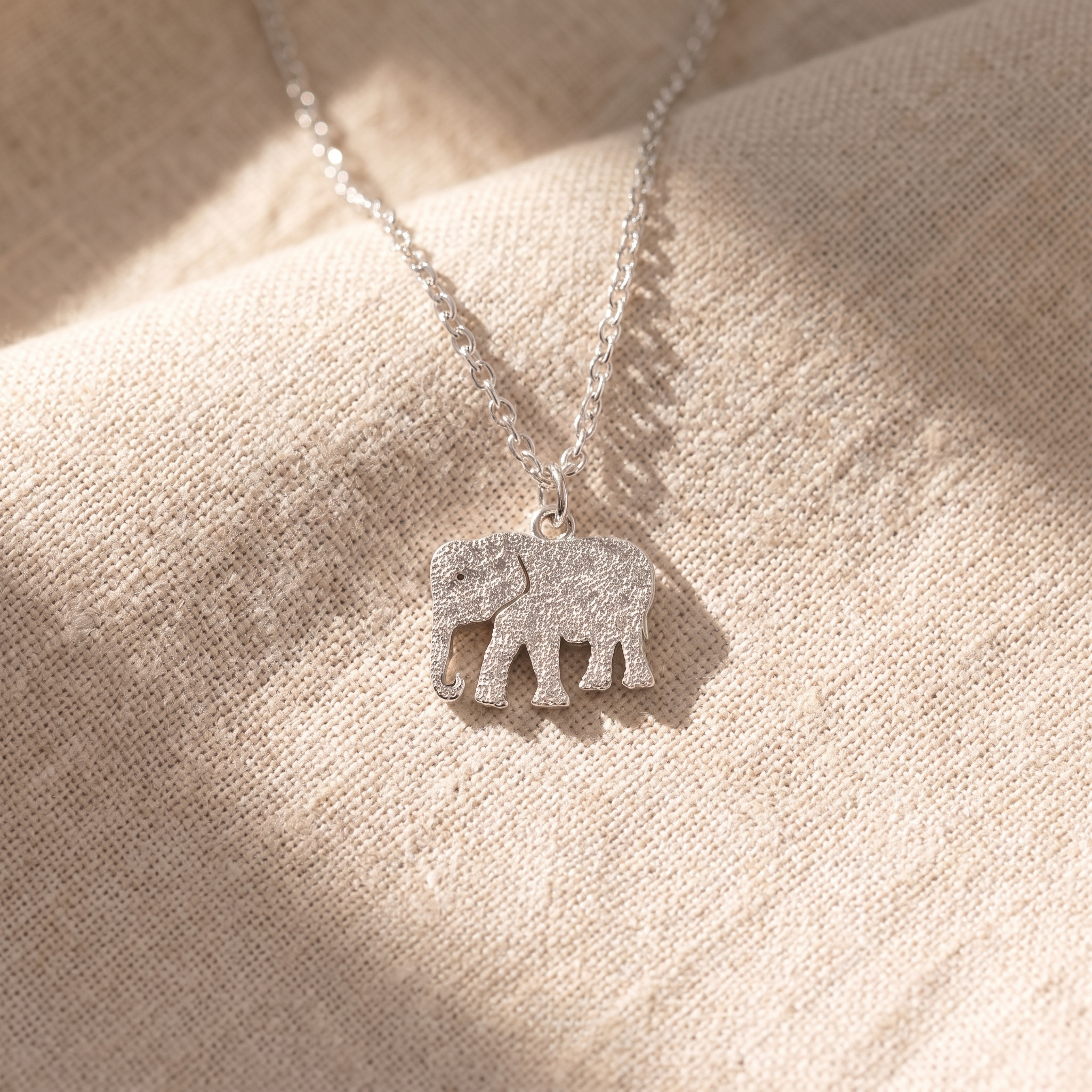 Four memorial keepsake pieces laid out on cream linen: a cremation pendant, an engraved name pendant, a handwriting pendant and a small keepsake urn