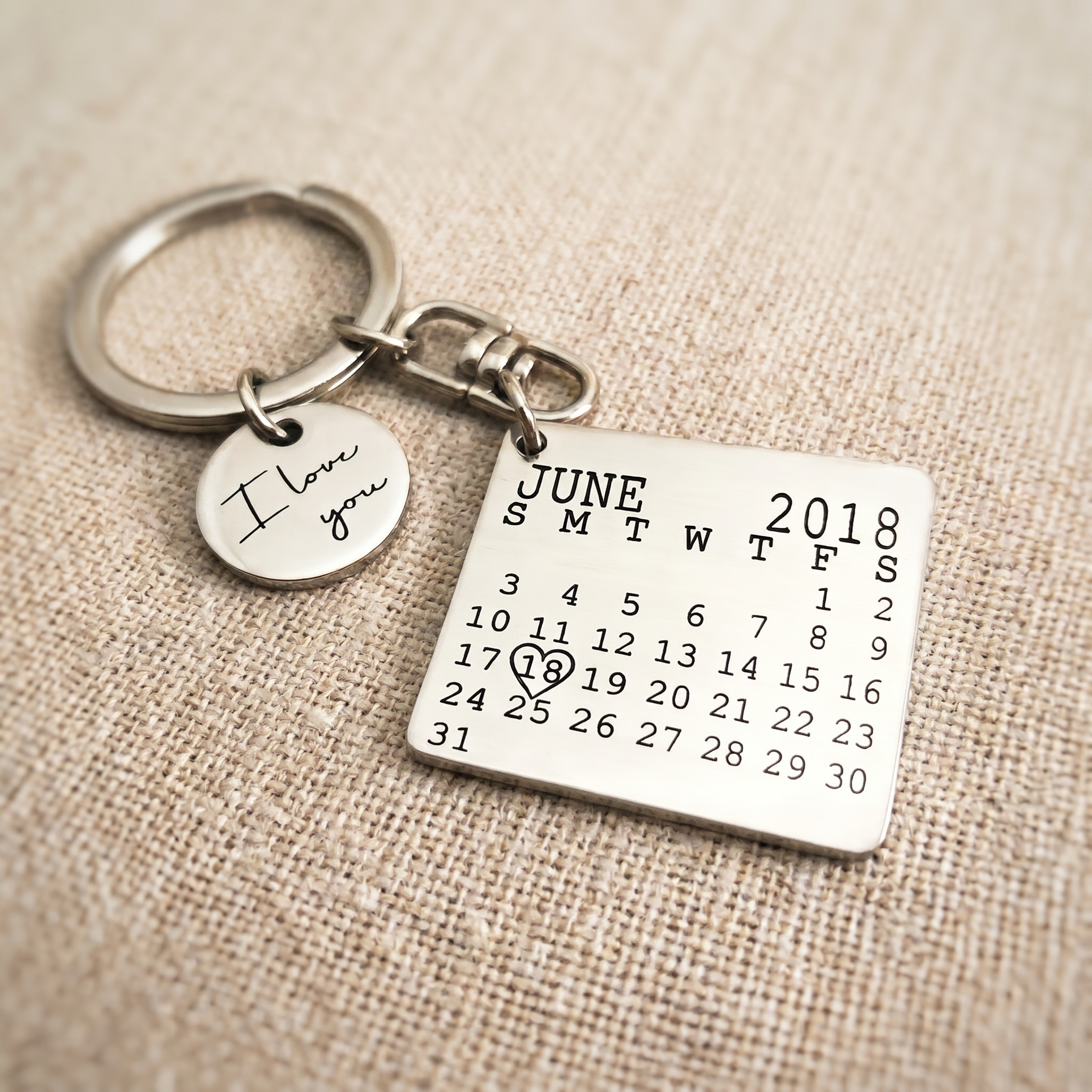 A pendant necklace and an engraved keyring laid side by side