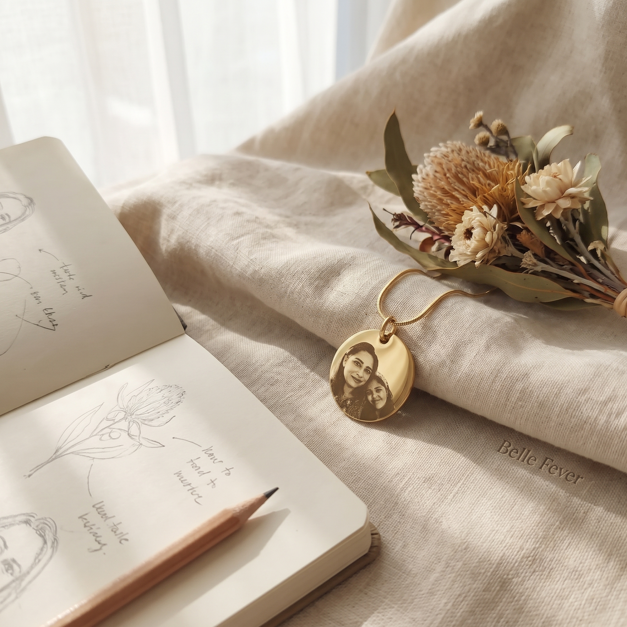 A pencil sketch of a pendant layout beside a finished pendant on a desk
