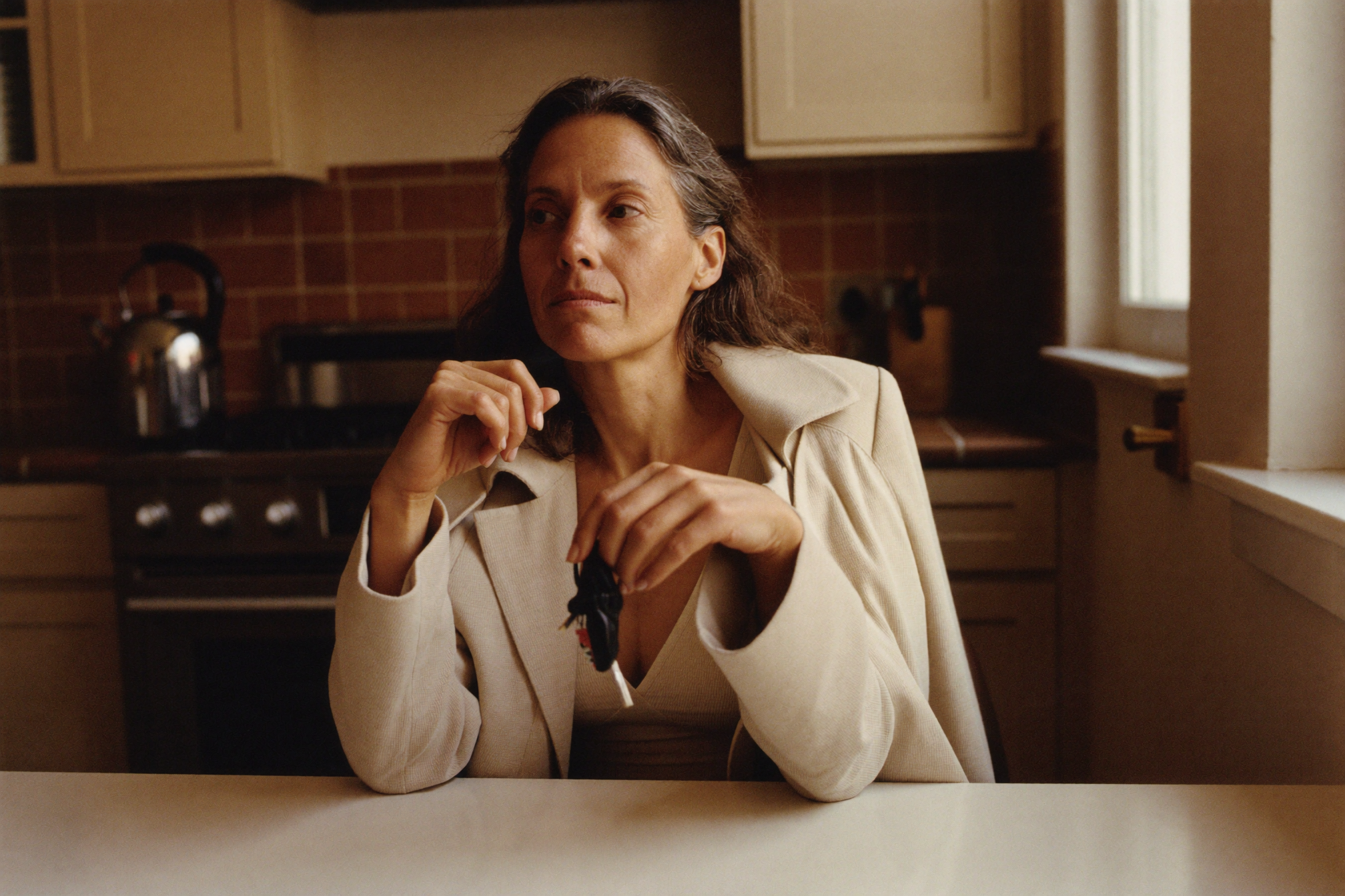 A woman in her fifties at her kitchen table in early morning light