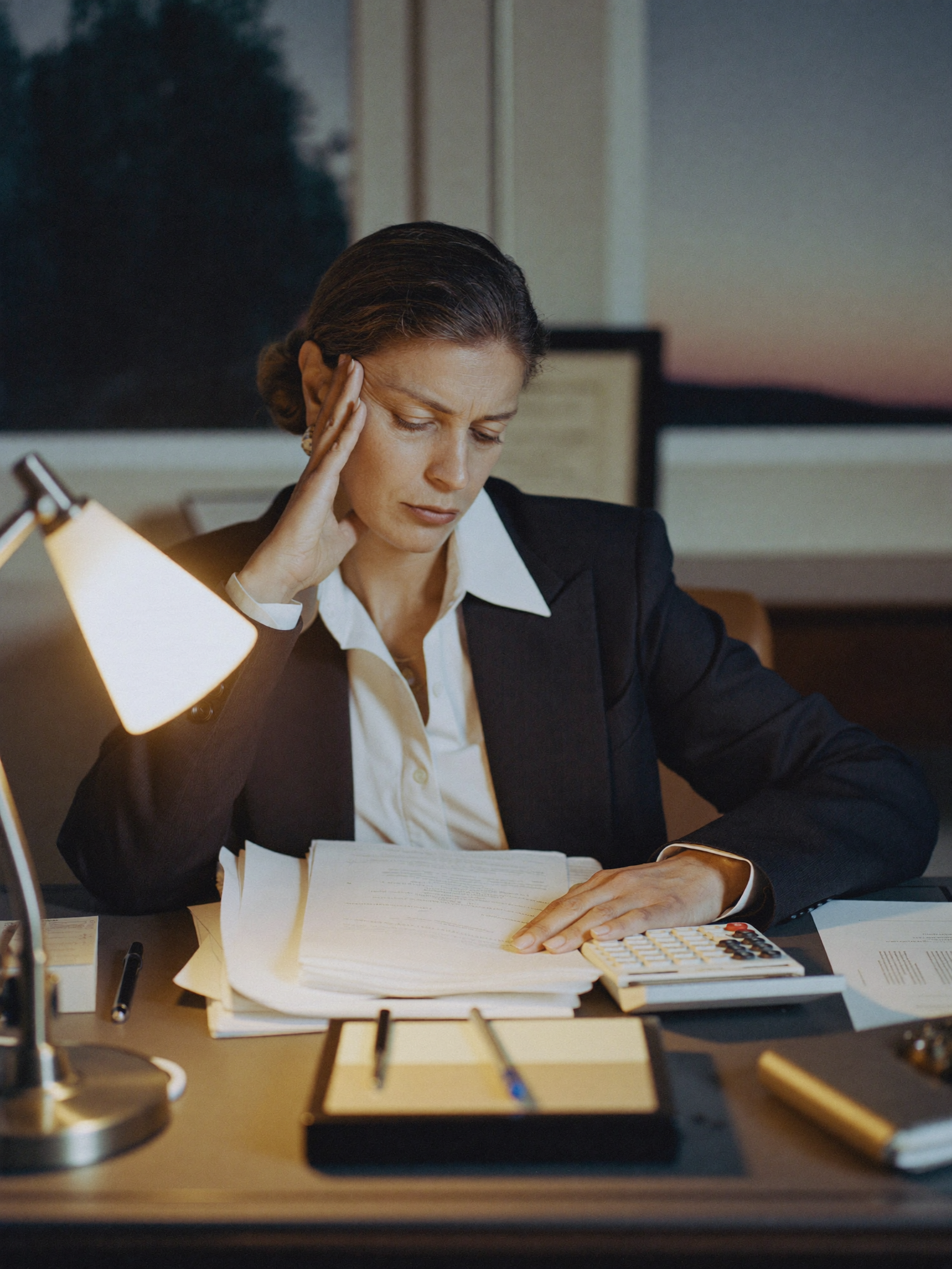 A woman surrounded by paperwork, overwhelmed by tax and financial documents.