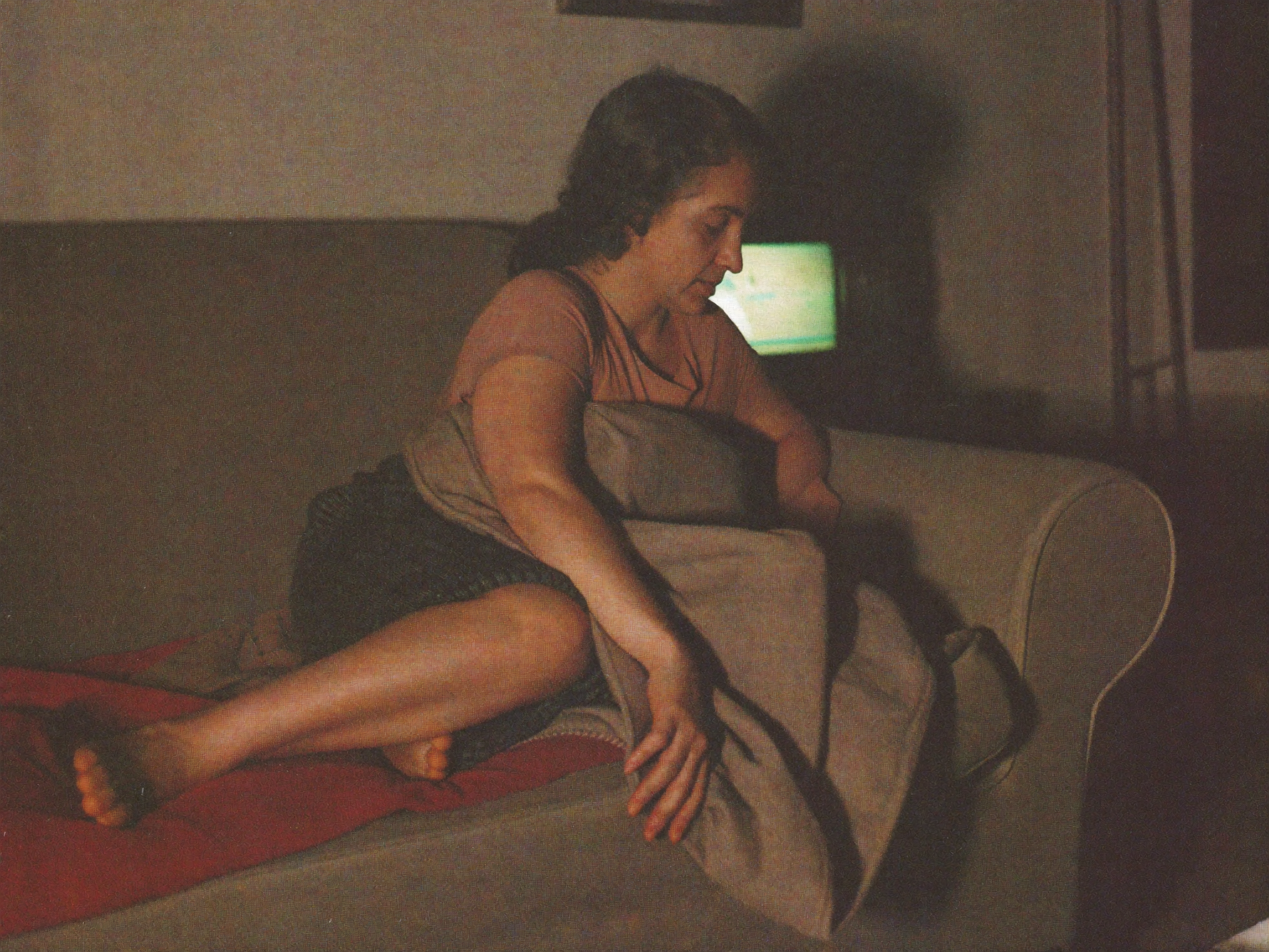 Femme épuisée sur son canapé le soir, se frottant la jambe