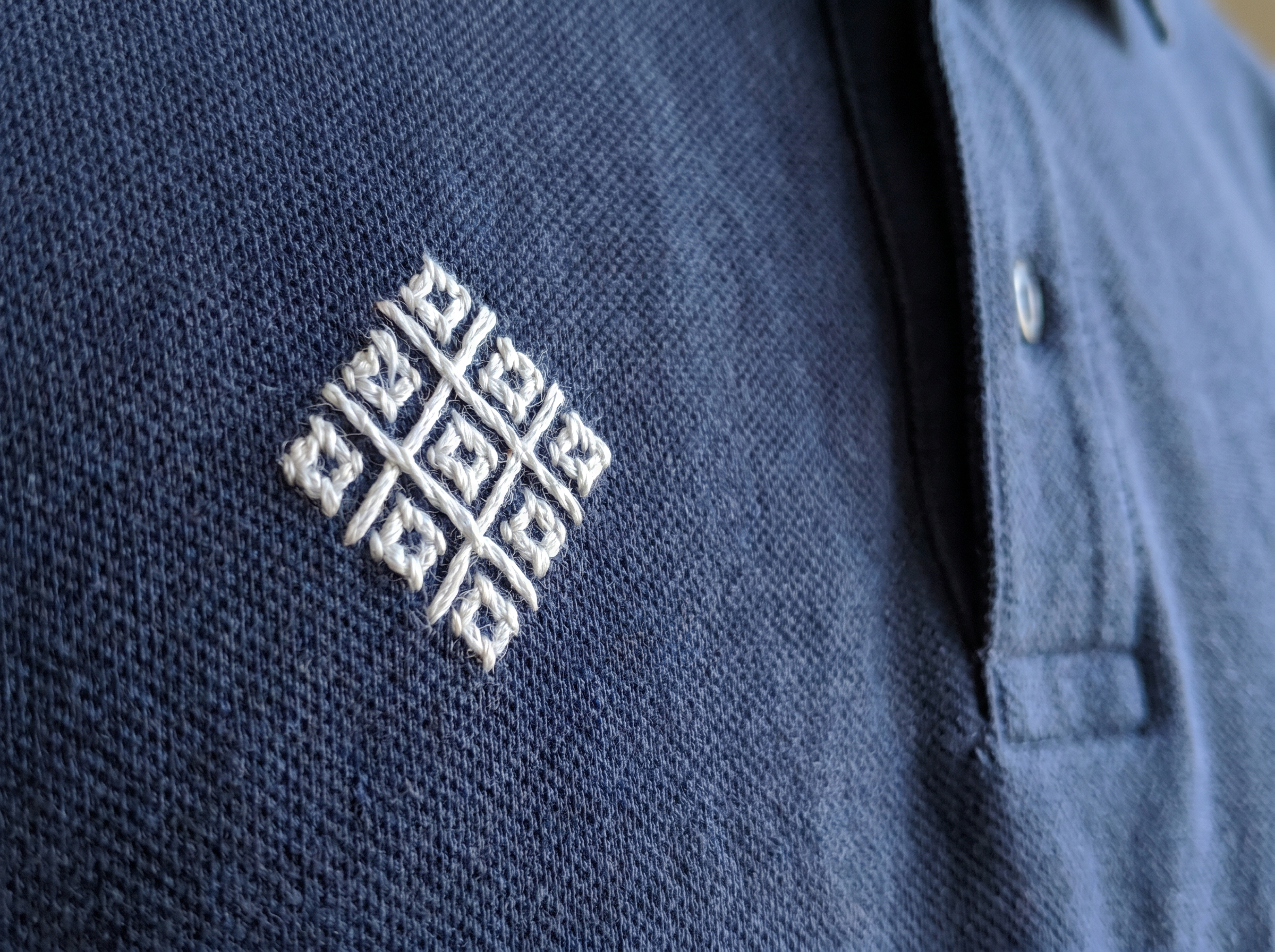 Custom embroidered logo on polo shirt left chest - close-up of thread detail and stitch quality on cotton pique fabric