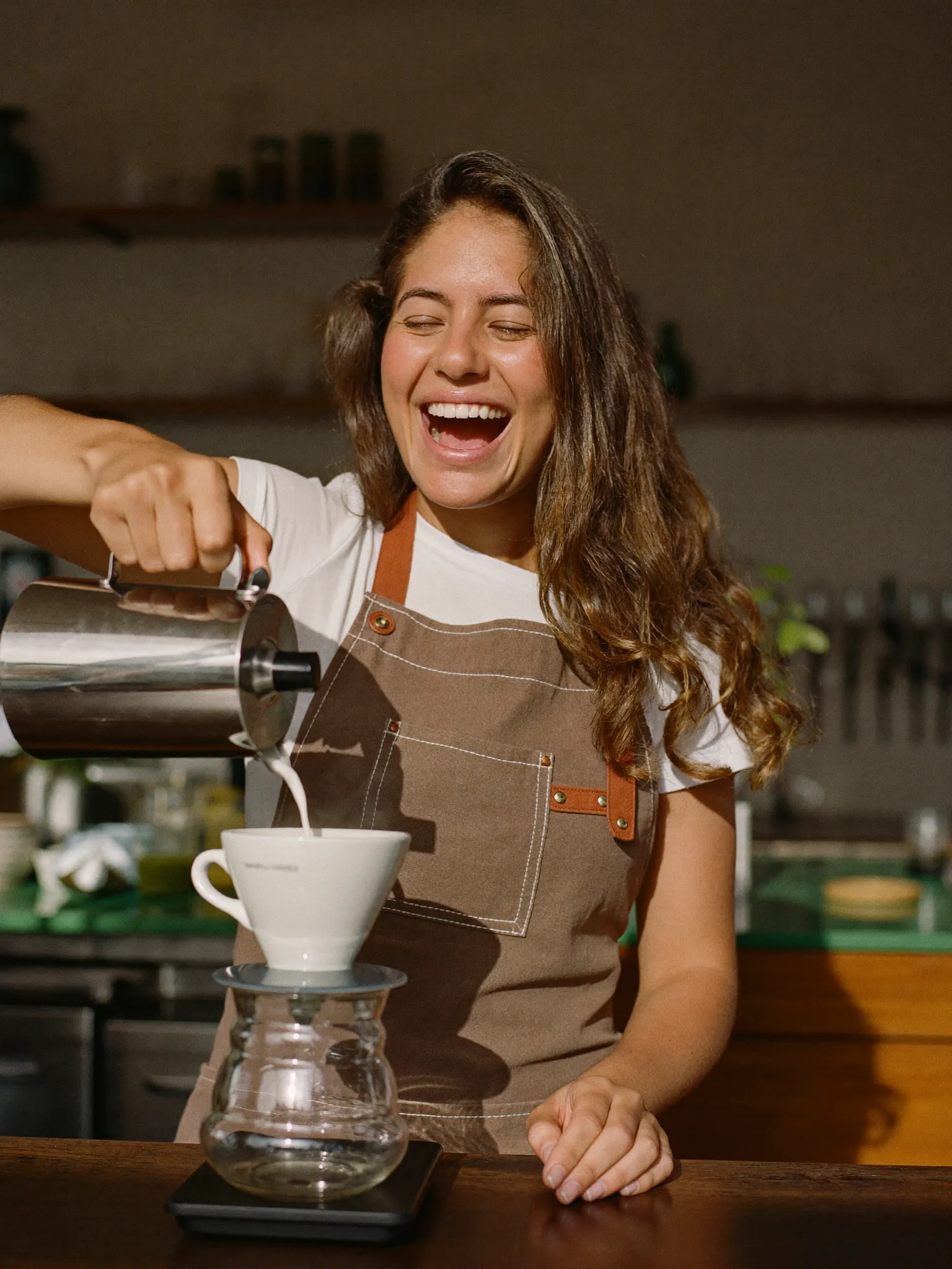 Barista behind the counter of a sunlit cafe