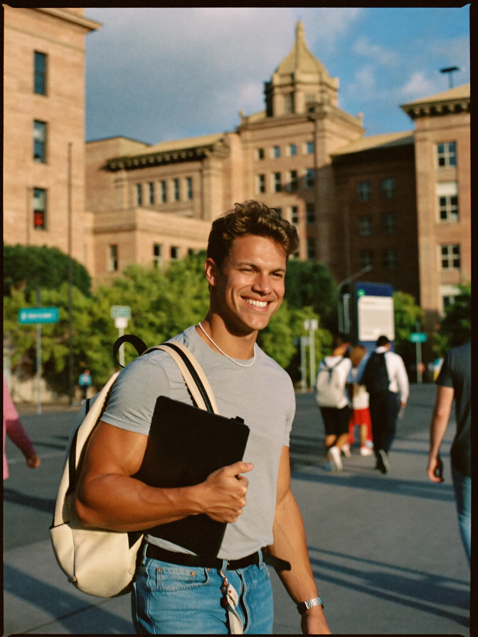 Recent graduate walking through a city campus