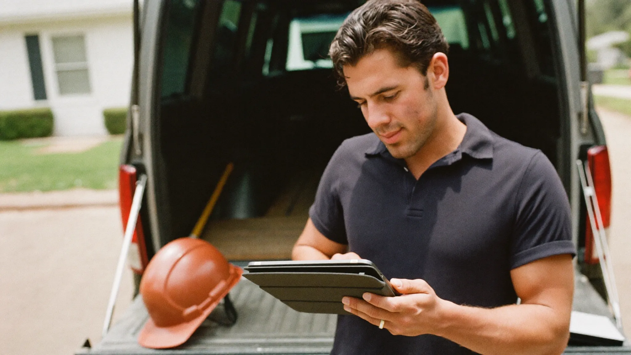 A contractor checking his schedule and pipeline on a tablet at the tailgate of his work truck