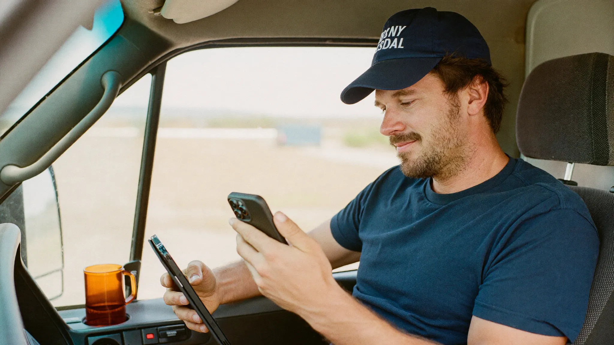 A residential contractor in his truck checking his schedule on a phone and tablet