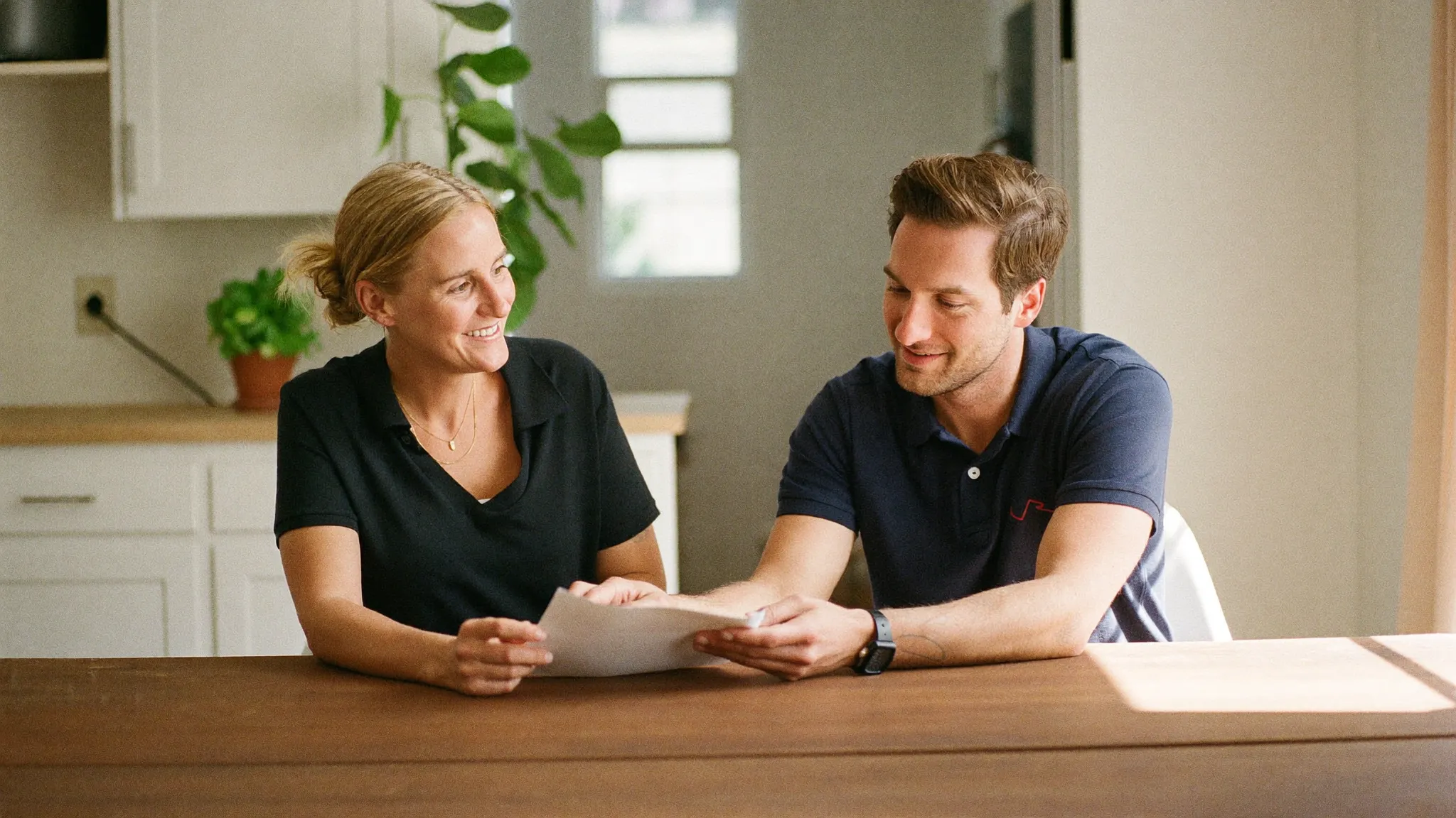 A contractor reviewing an insurance policy with an agent at a kitchen table