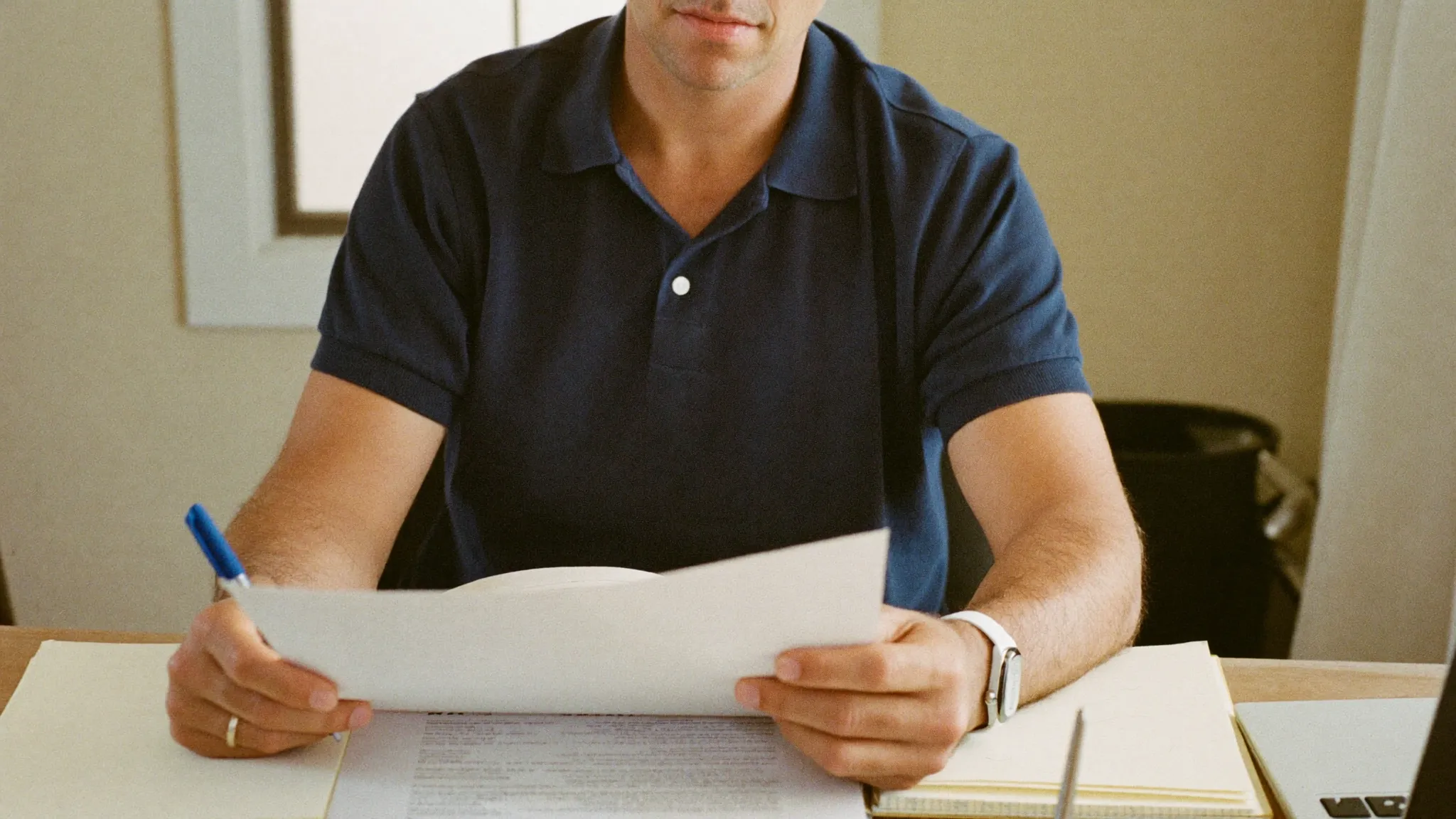 A contractor at his home-office desk reviewing an insurance policy
