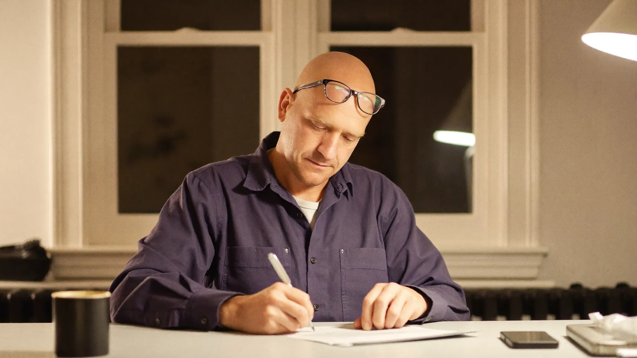 A residential painting contractor signing a lien waiver at his kitchen table in the evening