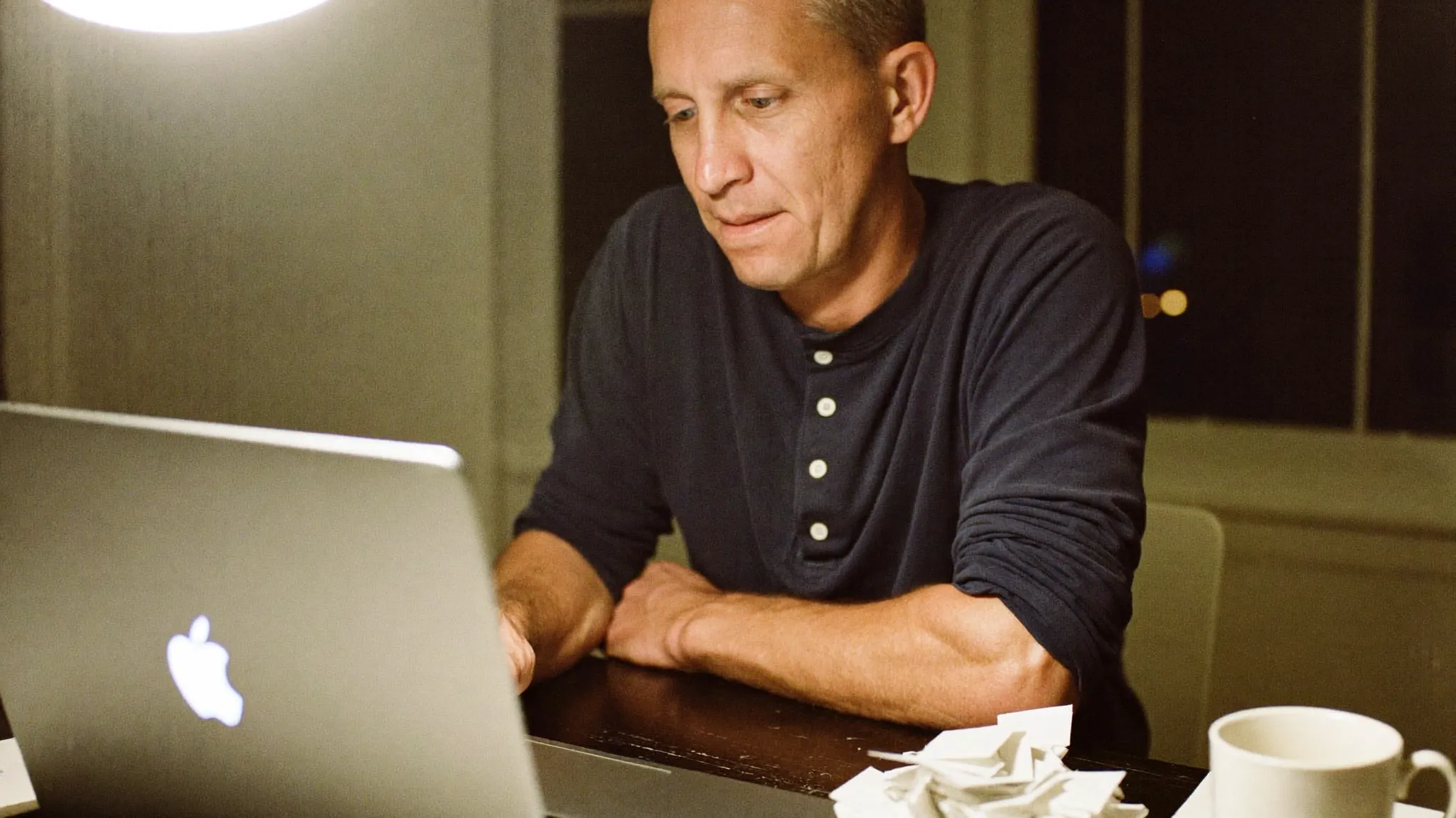 A residential contractor doing his books at the kitchen table on a laptop in the evening