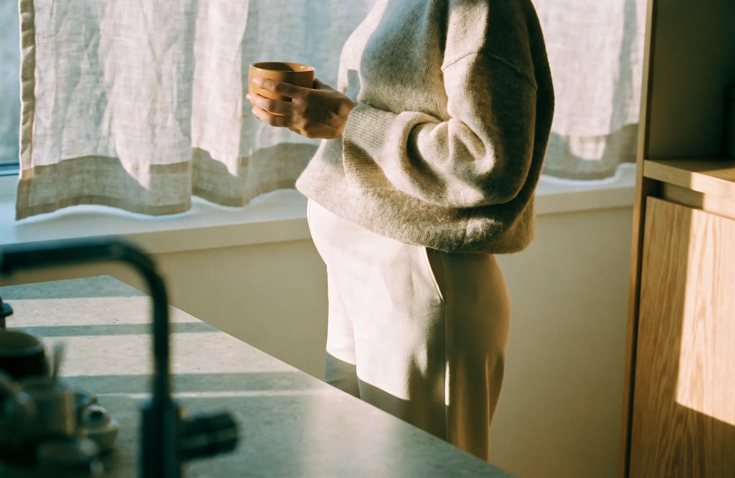 An expectant mother standing calmly at a sunlit kitchen counter