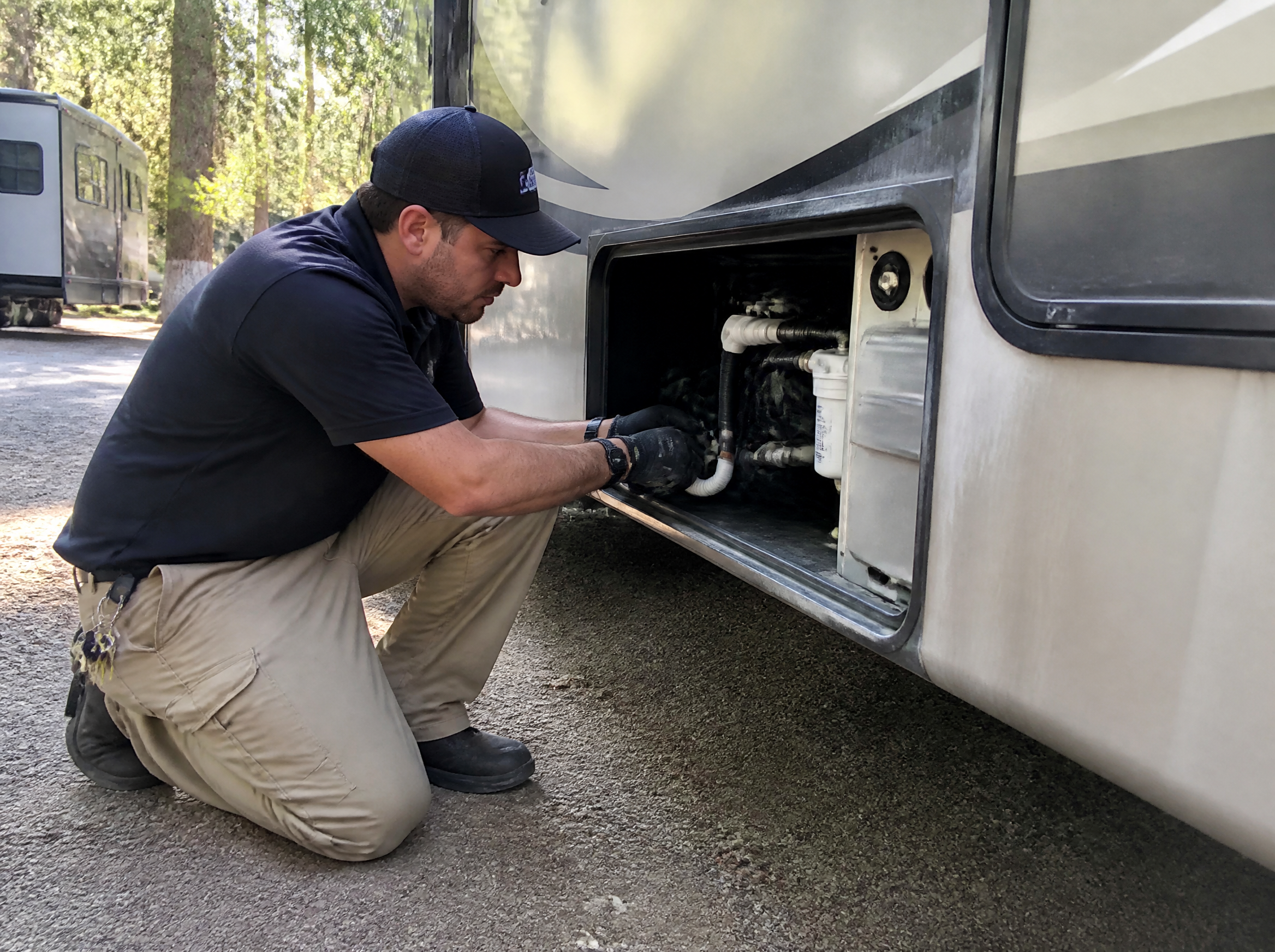 RV technician inspecting a utility bay on a parked RV for rodent entry points