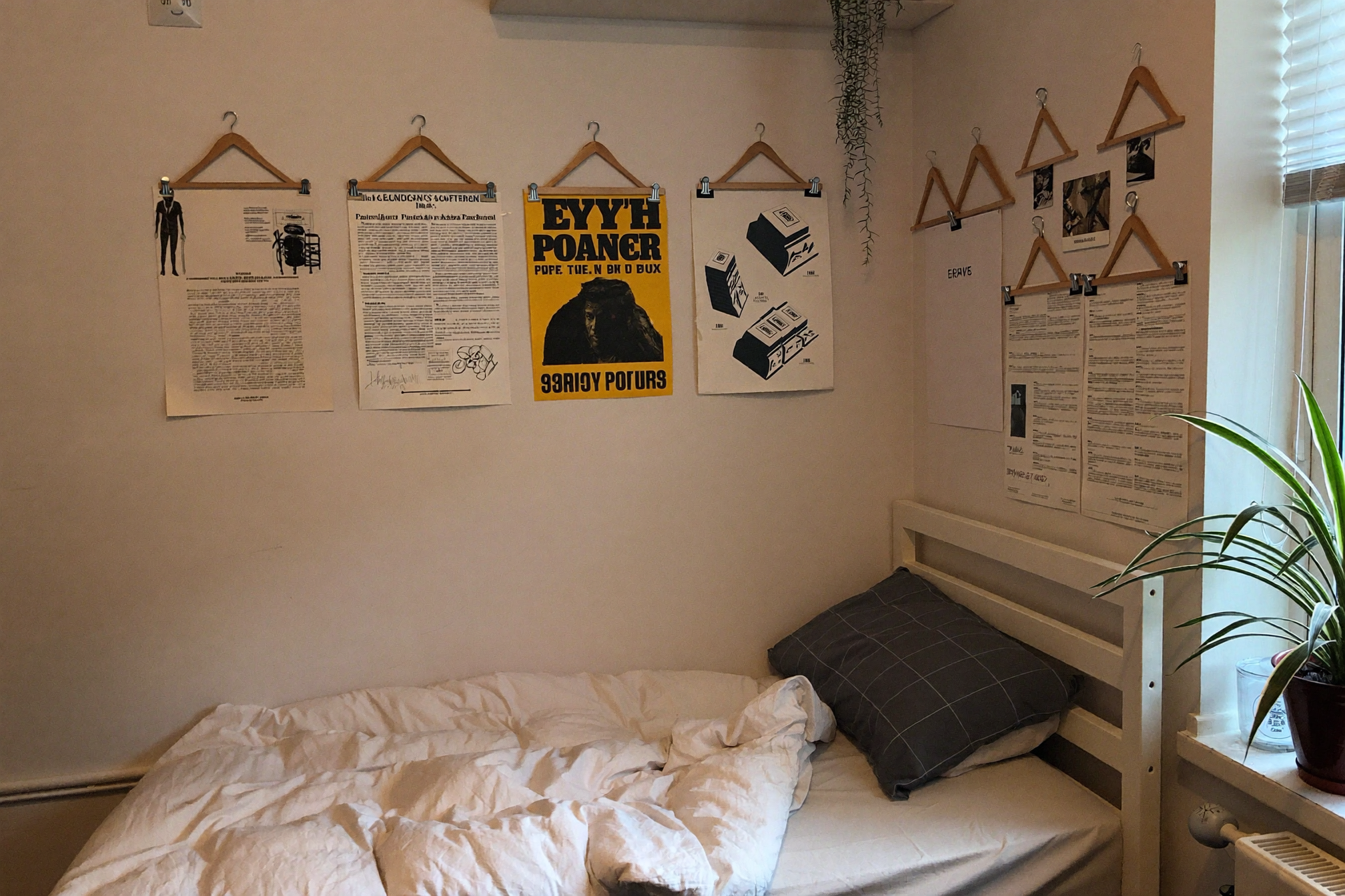 Small first apartment bedroom with unframed prints on wooden poster hangers