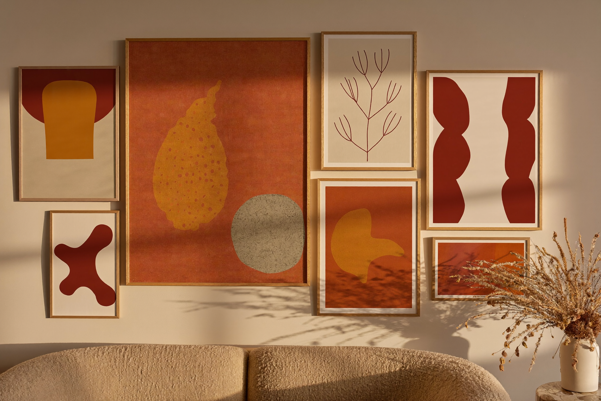 Warm autumn gallery wall with abstract and botanical prints above a beige sofa