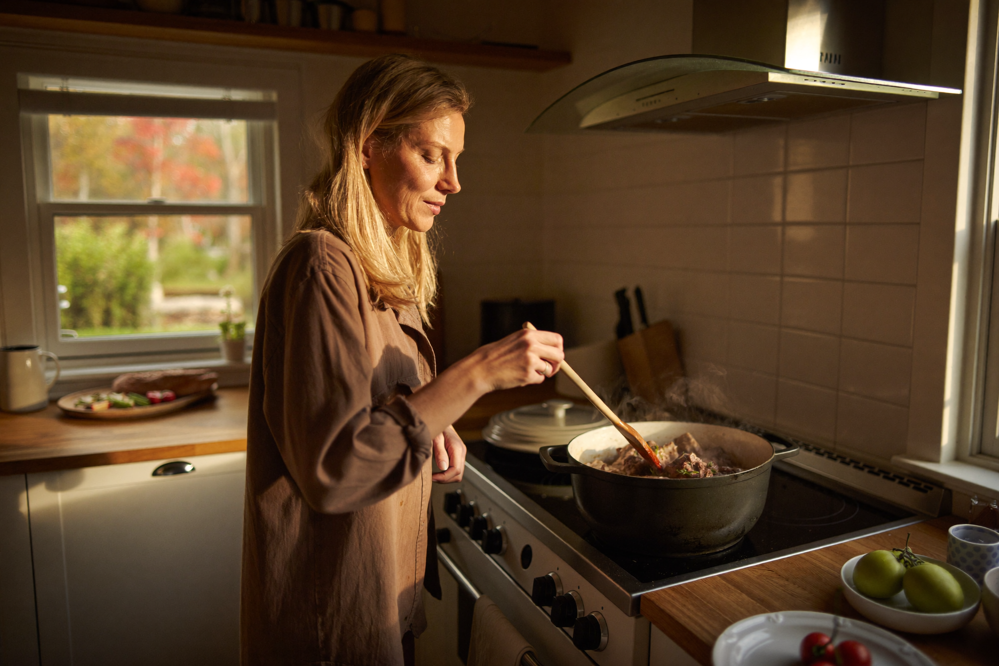 Vrouw roert in een braadpan met stoofvlees in een gezellige keuken