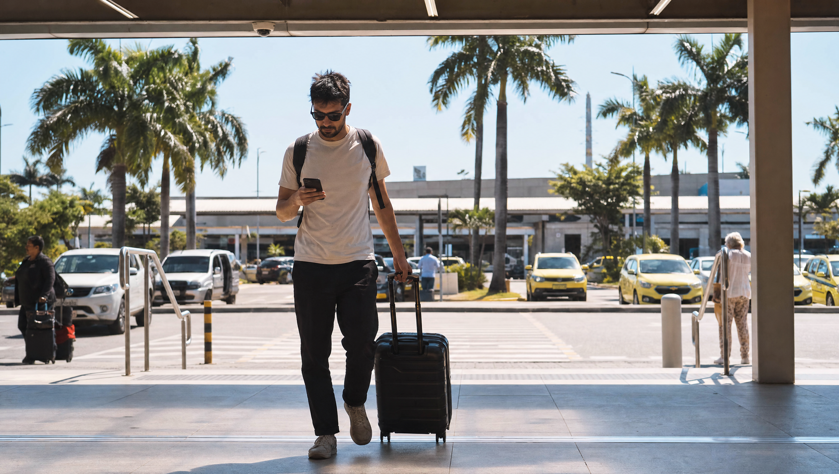 Voyageuse à la sortie de l'aéroport de São Paulo, valise à roulettes, téléphone à la main