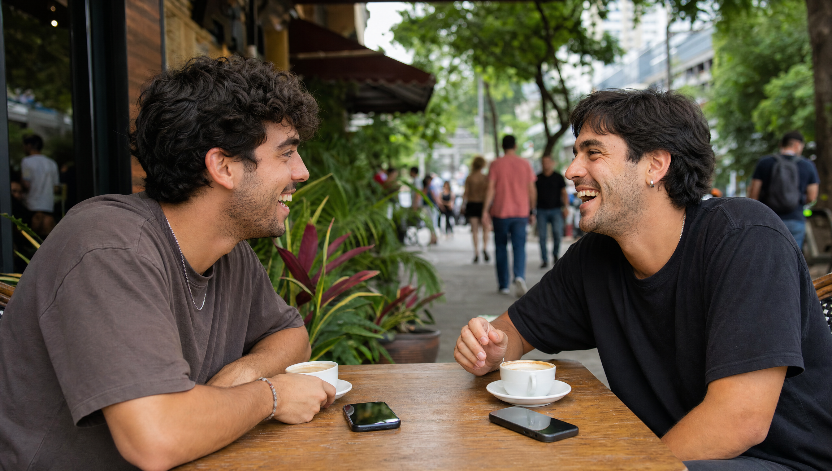 Deux amis attablés à un café à Medellín, téléphones posés sur la table