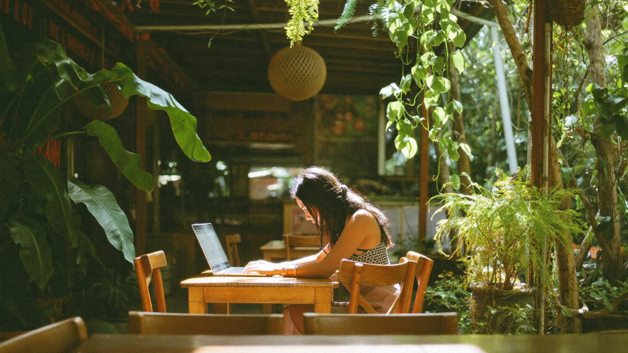 Traveller working on a laptop at an open-air café in Chiang Mai, surrounded by tropical greenery