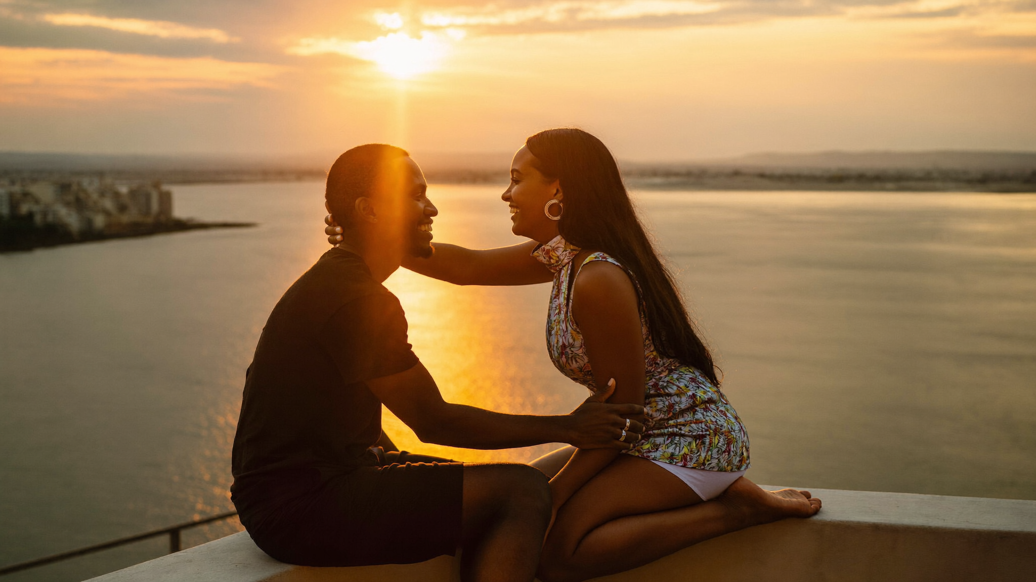 Couple de voyageurs sur une terrasse avec vue sur la lagune d'Abidjan, lumière chaude en soirée