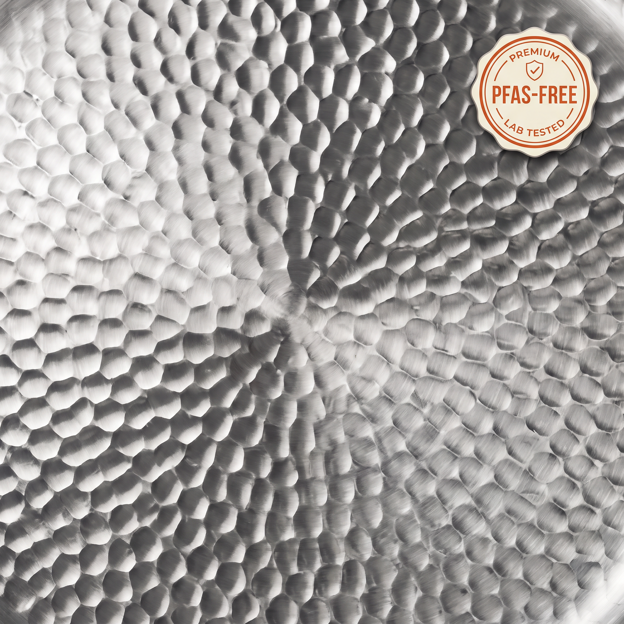 Top-down close-up of the hand-hammered titanium cooking surface of an Iron Crown pan with a PFAS-free lab-tested seal