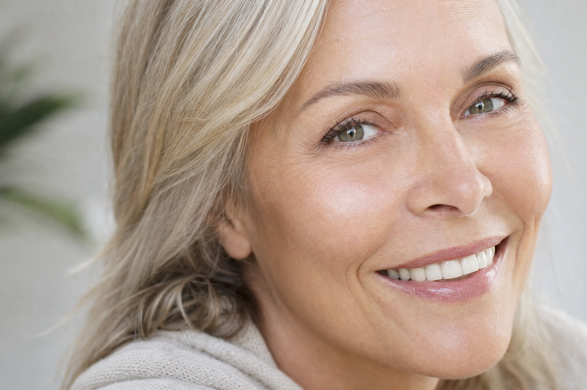 Woman smiling with hands framing her face, highlighting brighter under-eyes