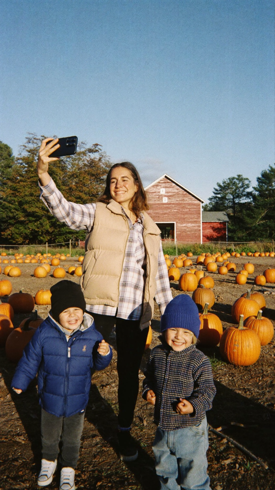 A mom filming herself and her kids at a pumpkin patch