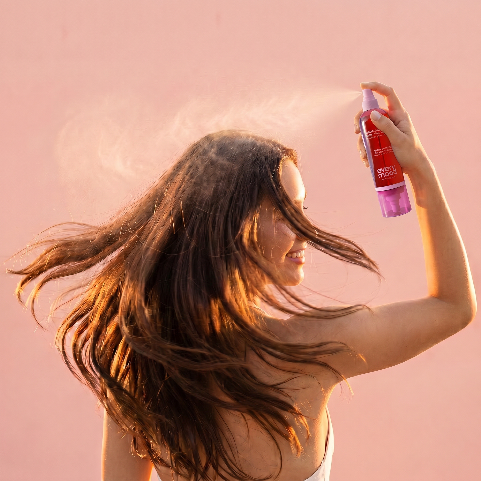 Woman with shiny healthy hair spritzing Berry Obsessed mist