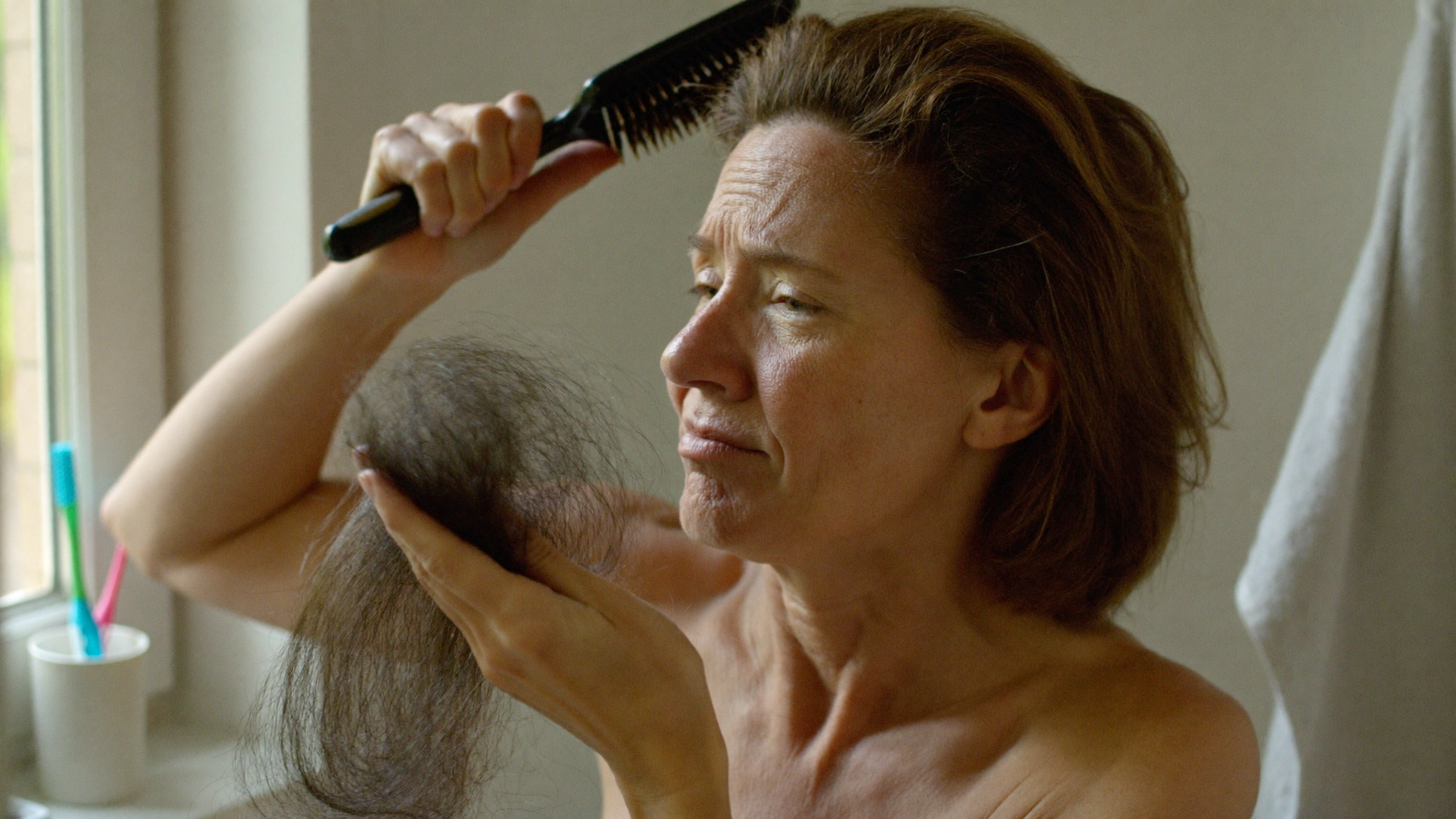 Vrouw kijkt naar het haar in haar haarborstel