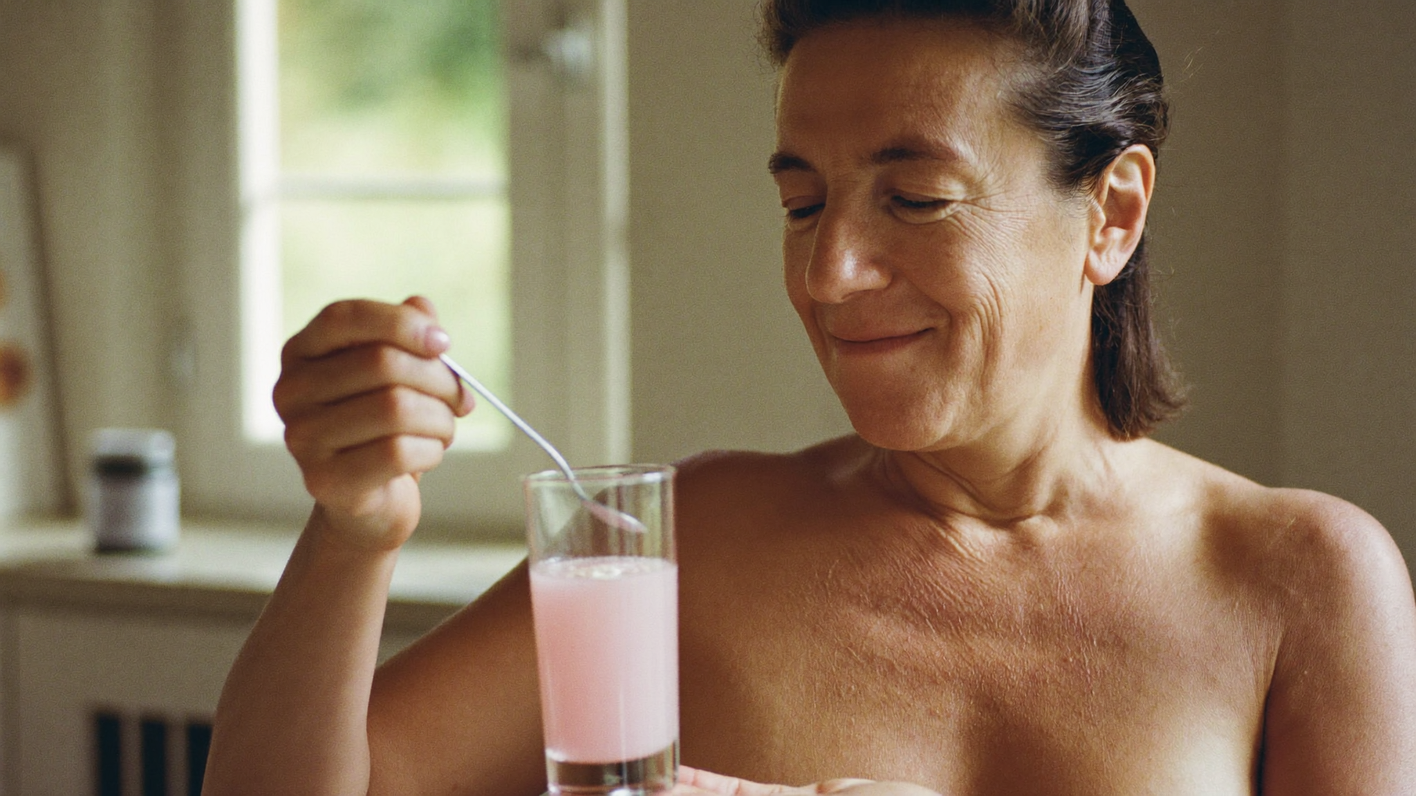 Vrouw drinkt een glas opgelost collageen in de keuken