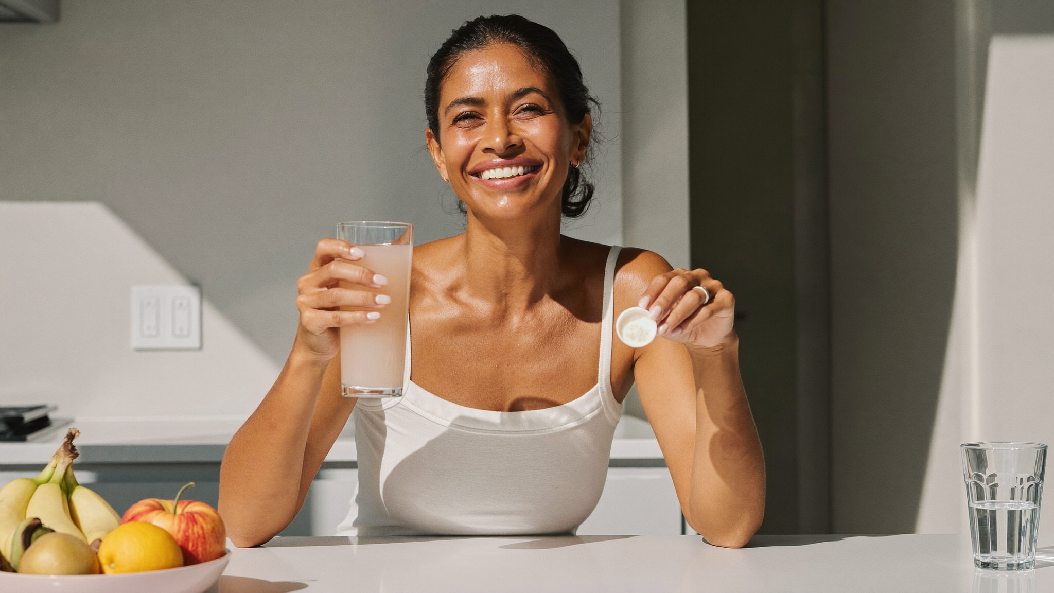 Vrouw met een glas opgelost collageen in de keuken