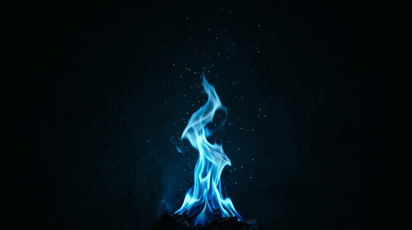 A flame burning sky blue against the dark