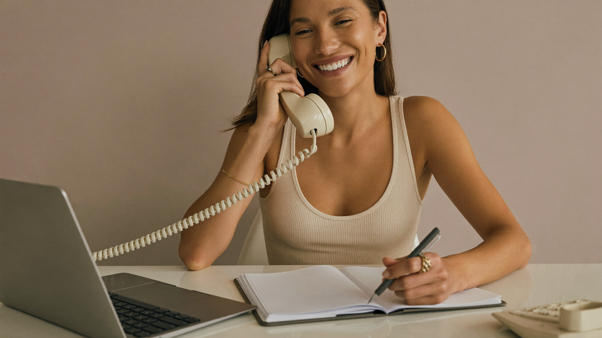A patient coordinator on the phone taking notes at her desk