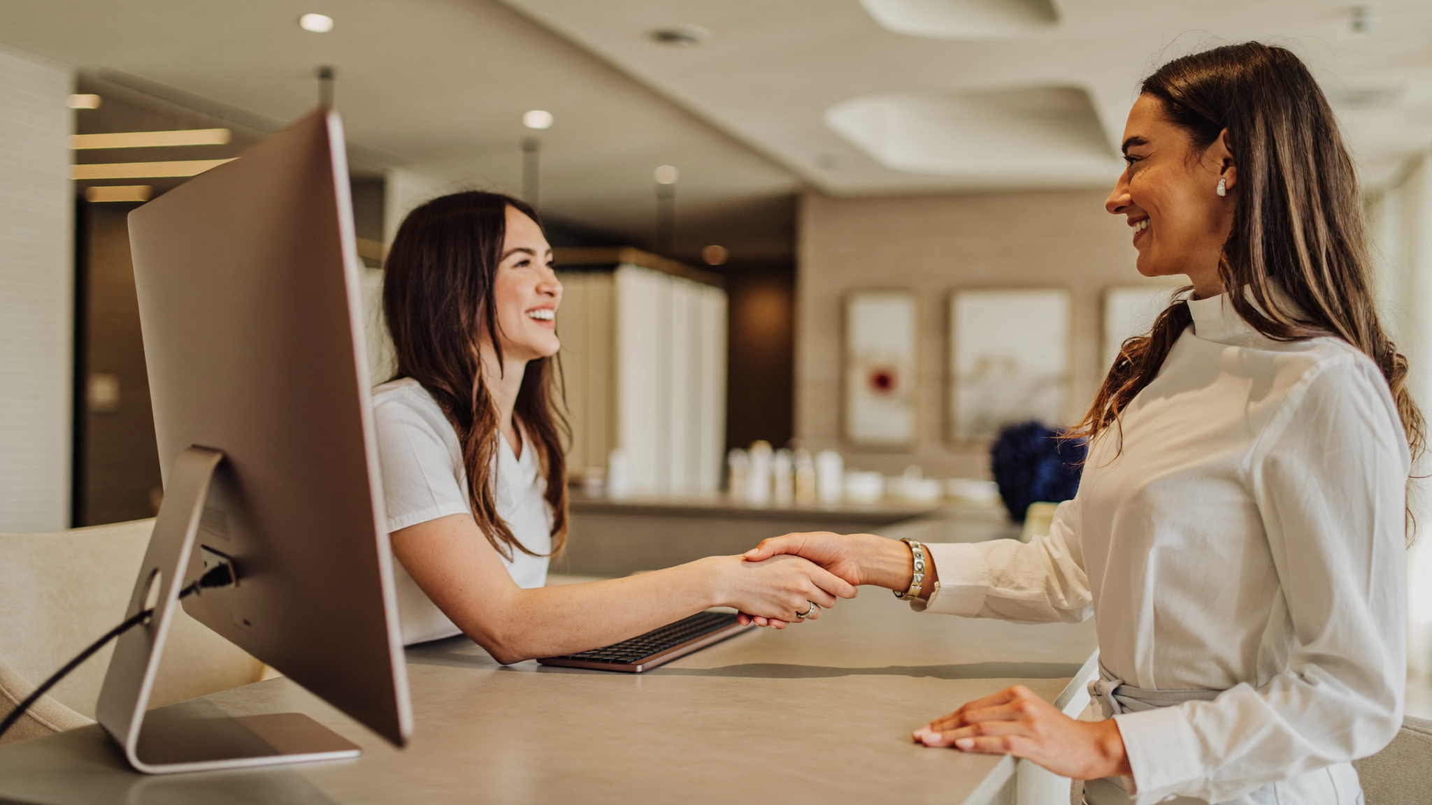 A practice staff member warmly welcoming a patient at the front desk