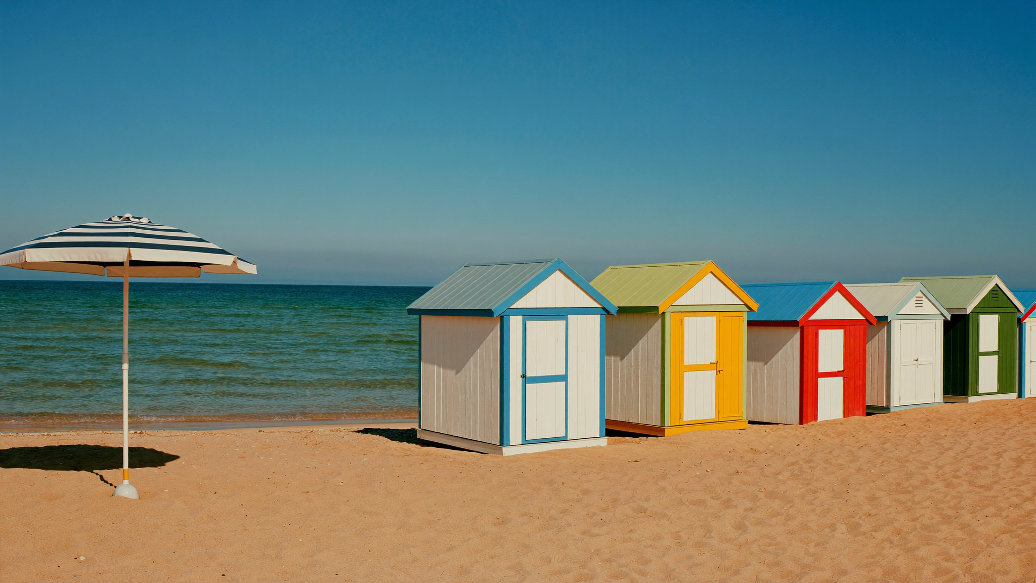 Dansk badestrand med badehuse i strålende sommersol
