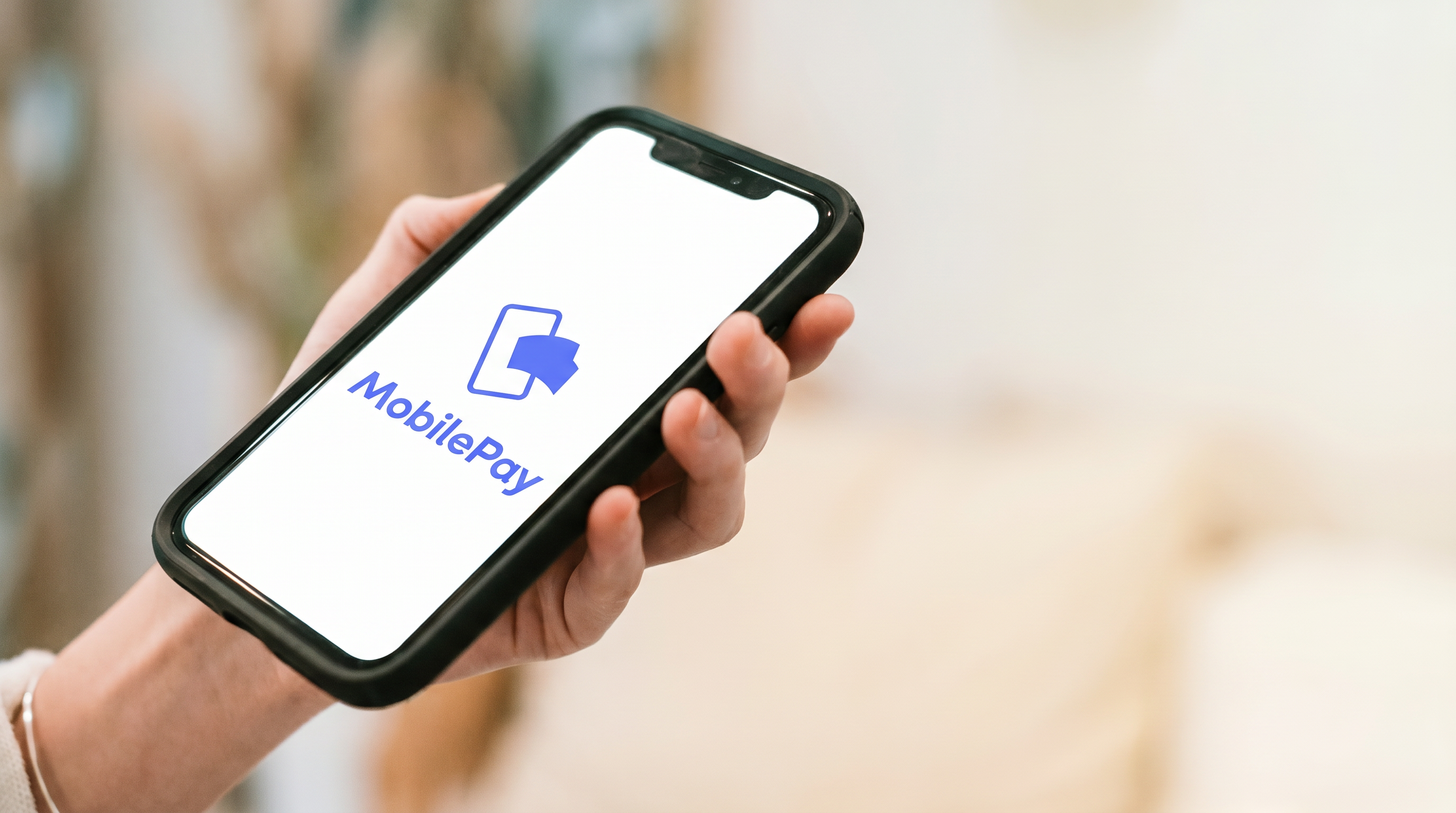 Hånd der holder en telefon med MobilePay-appen åben
