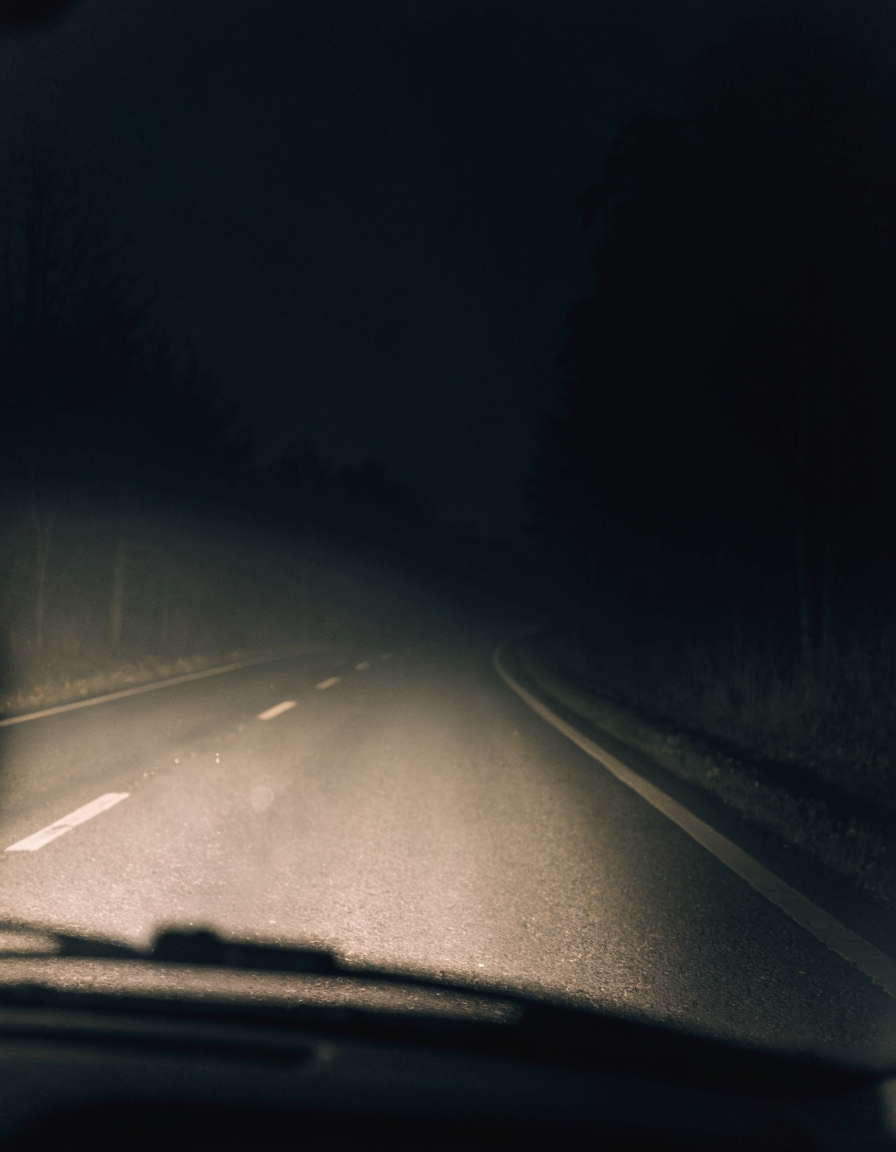 Night POV: weak murky headlight beam barely reaching the road