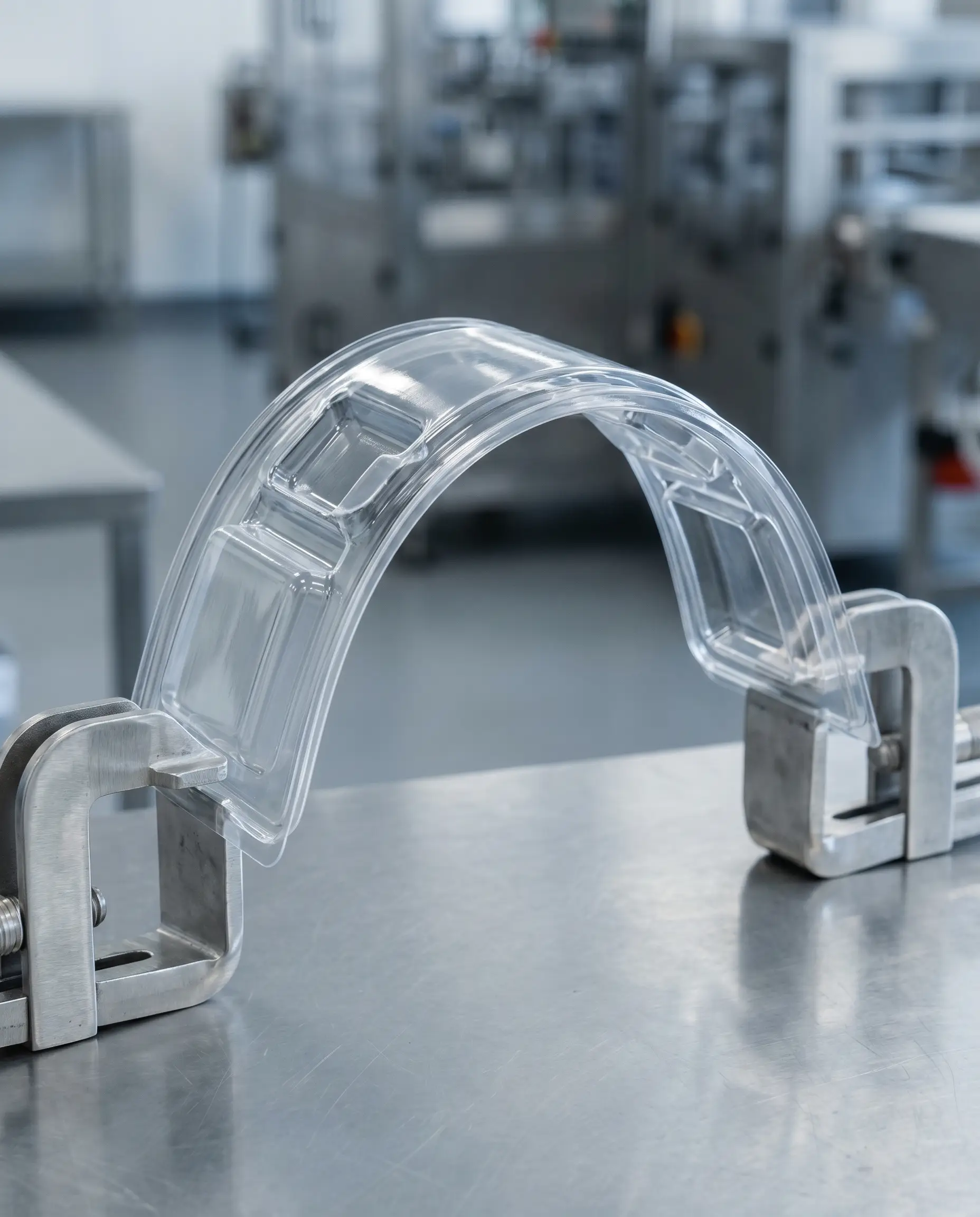 Hand holding a formed clear PETG tray — it flexes without whitening or cracking