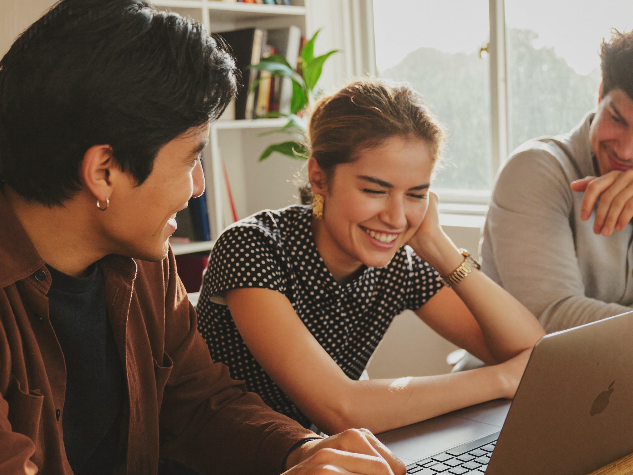 Two people collaborating around a laptop in a bright office