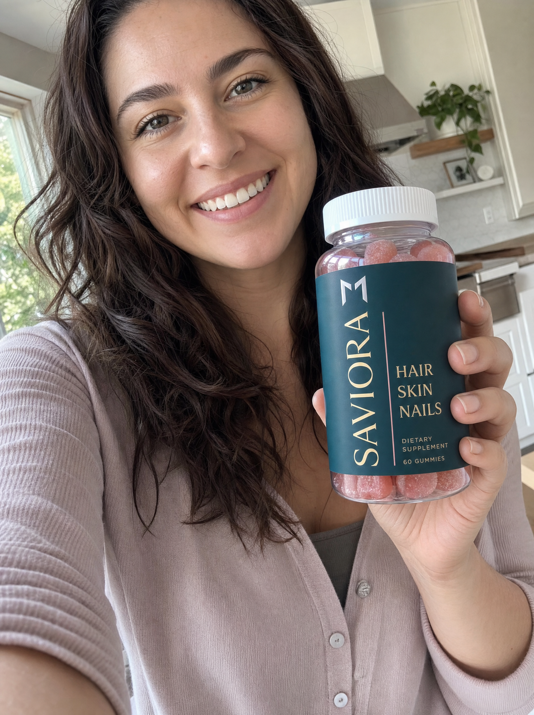 Woman holding Saviora Hair.Skin.Nails bottle in her kitchen