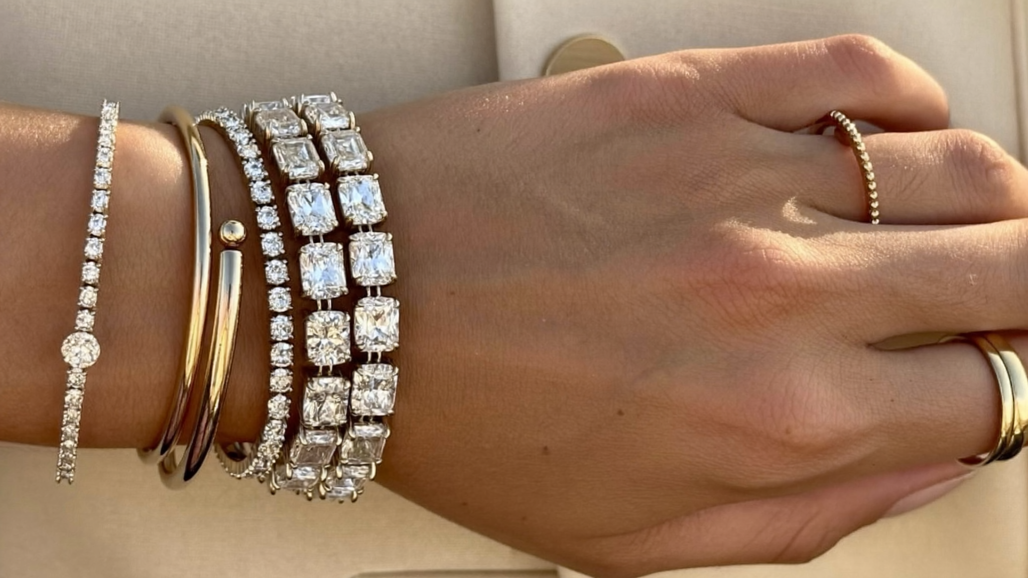 Stacked lab-grown diamond tennis bracelets in yellow and rose gold on a woman's wrist