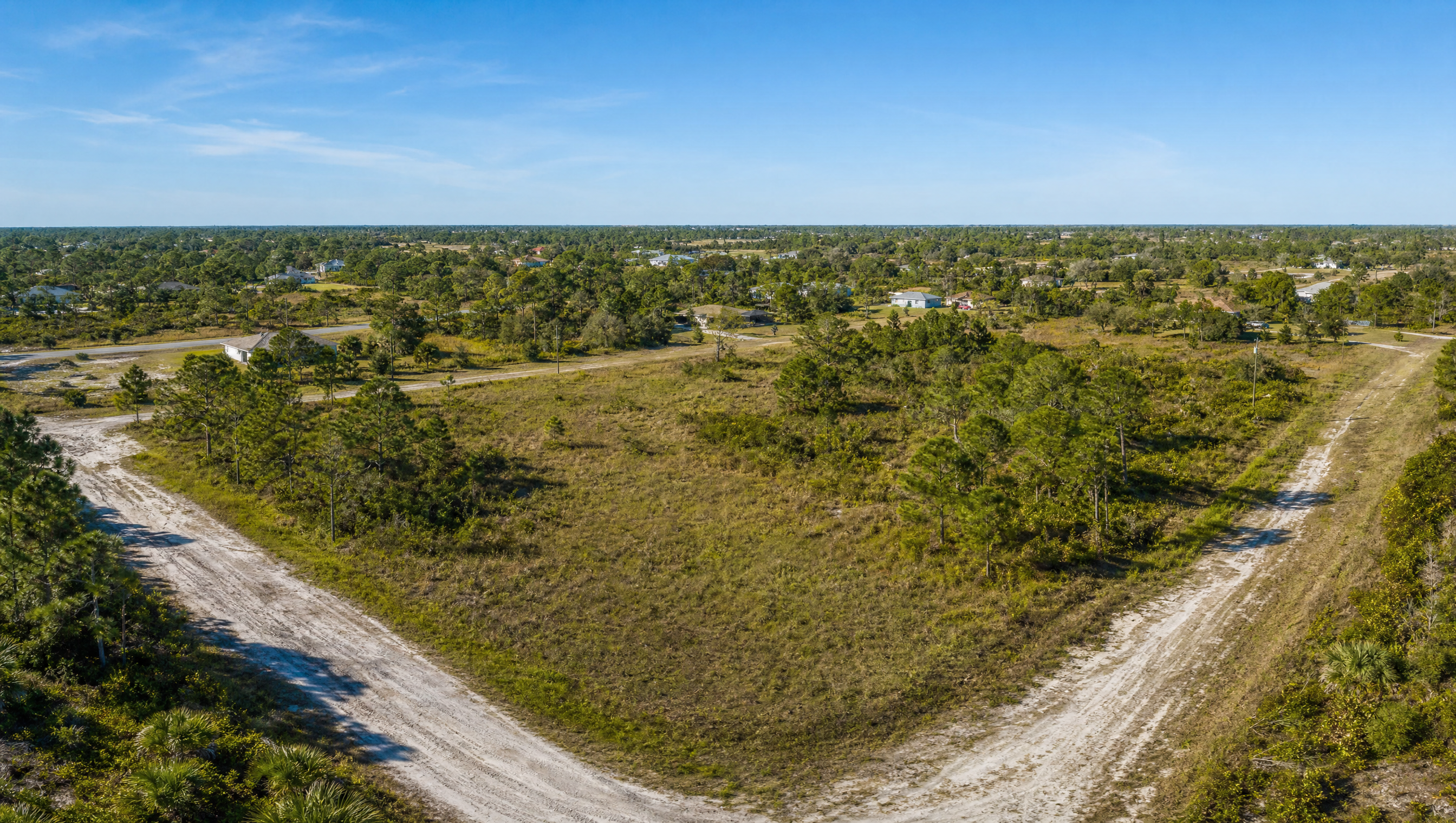 Aerial view of an empty Florida residential lot with dirt roads and pine trees