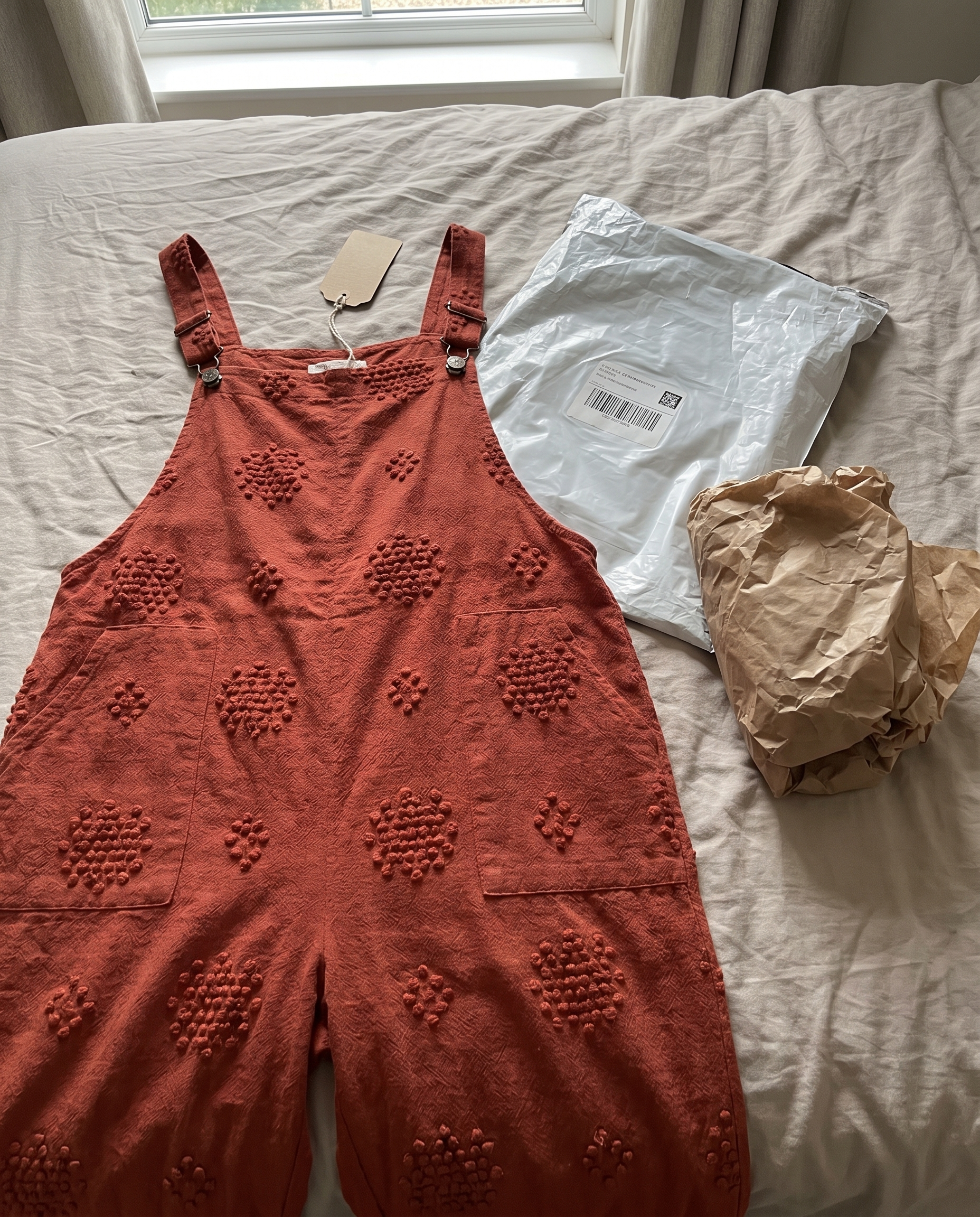 Flora Brick Red Jumpsuit unboxed on a bed